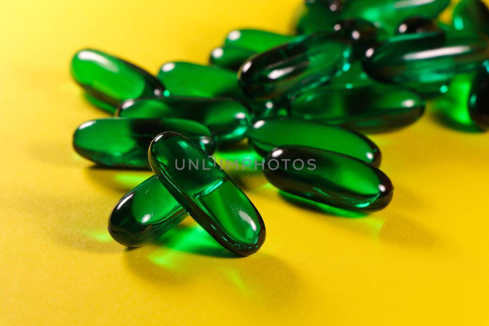 Green Essential Oil Pill Capsules On Bright Yellow by jjvanginkel