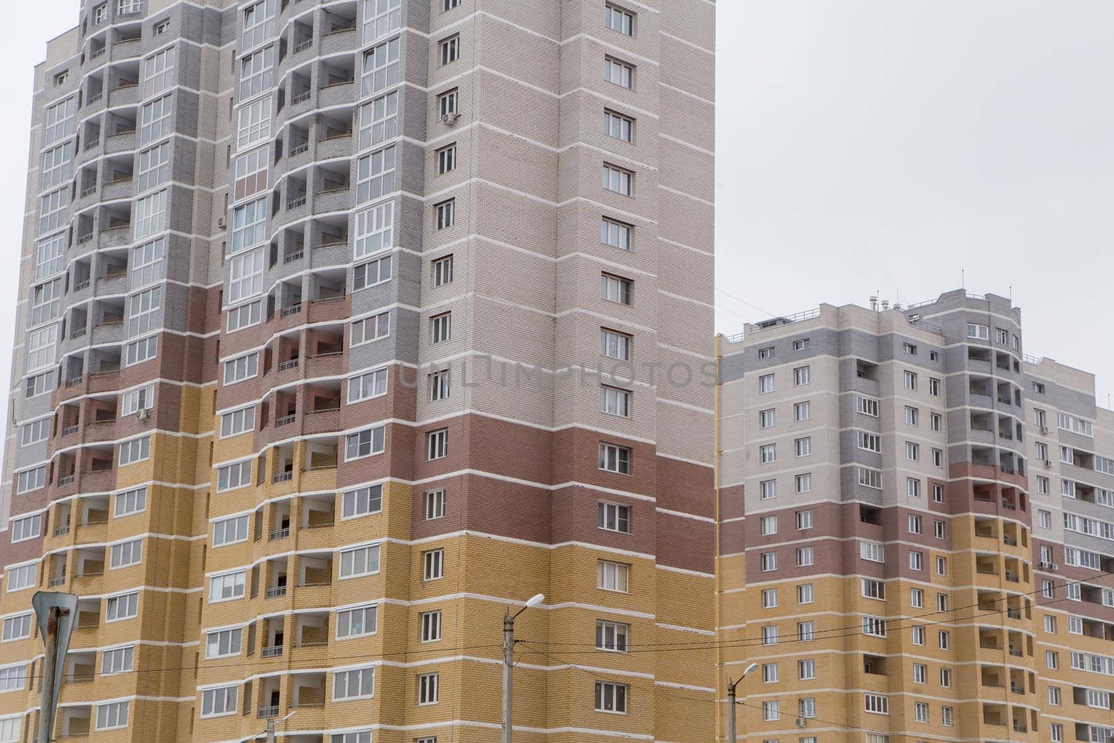 High-rise residential buildings in a new area of the city made of bricks. Against the background of the gray sky. Modern new buildings, building facades. Real estate and urban architecture concept.