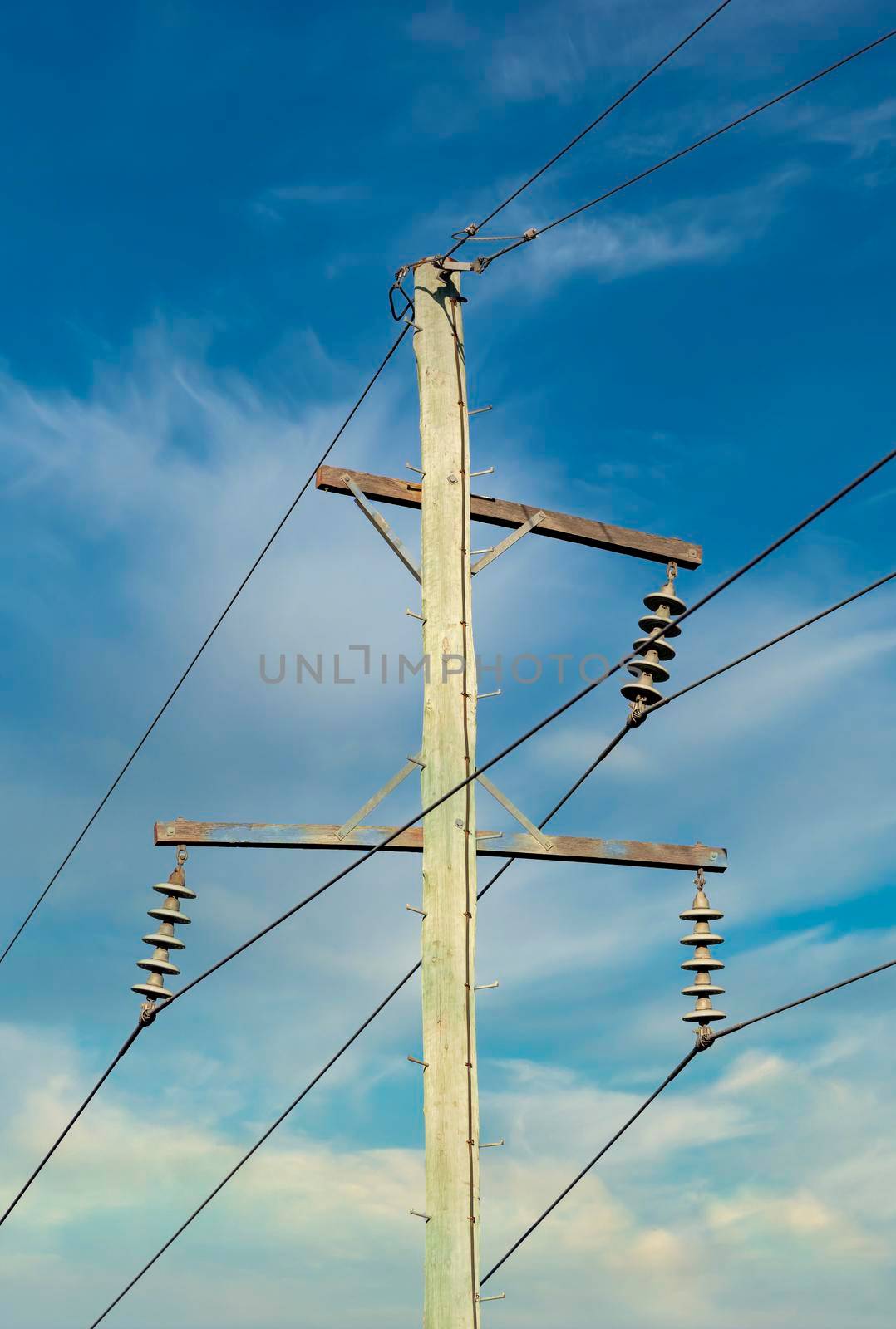 Photograph of a wooden telephone post and cables against a blue sky