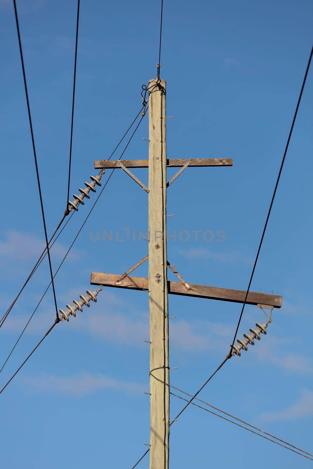 Photograph of a wooden telephone post and cables against a blue sky