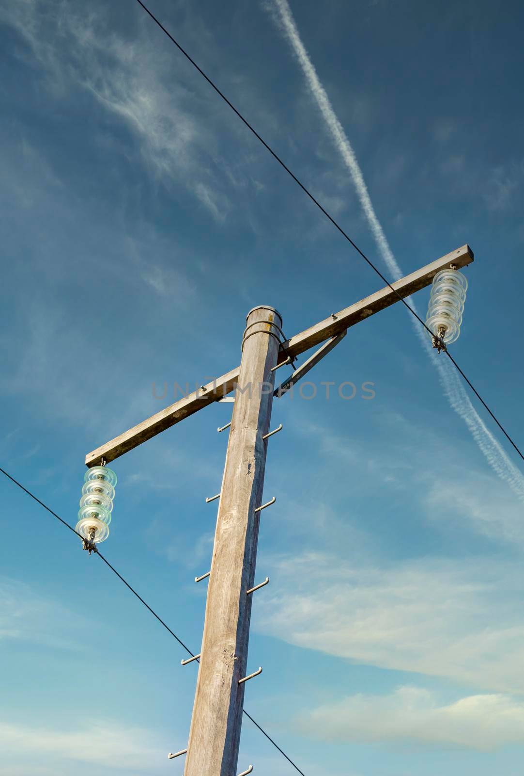 Photograph of a wooden telephone post and cables against a blue sky