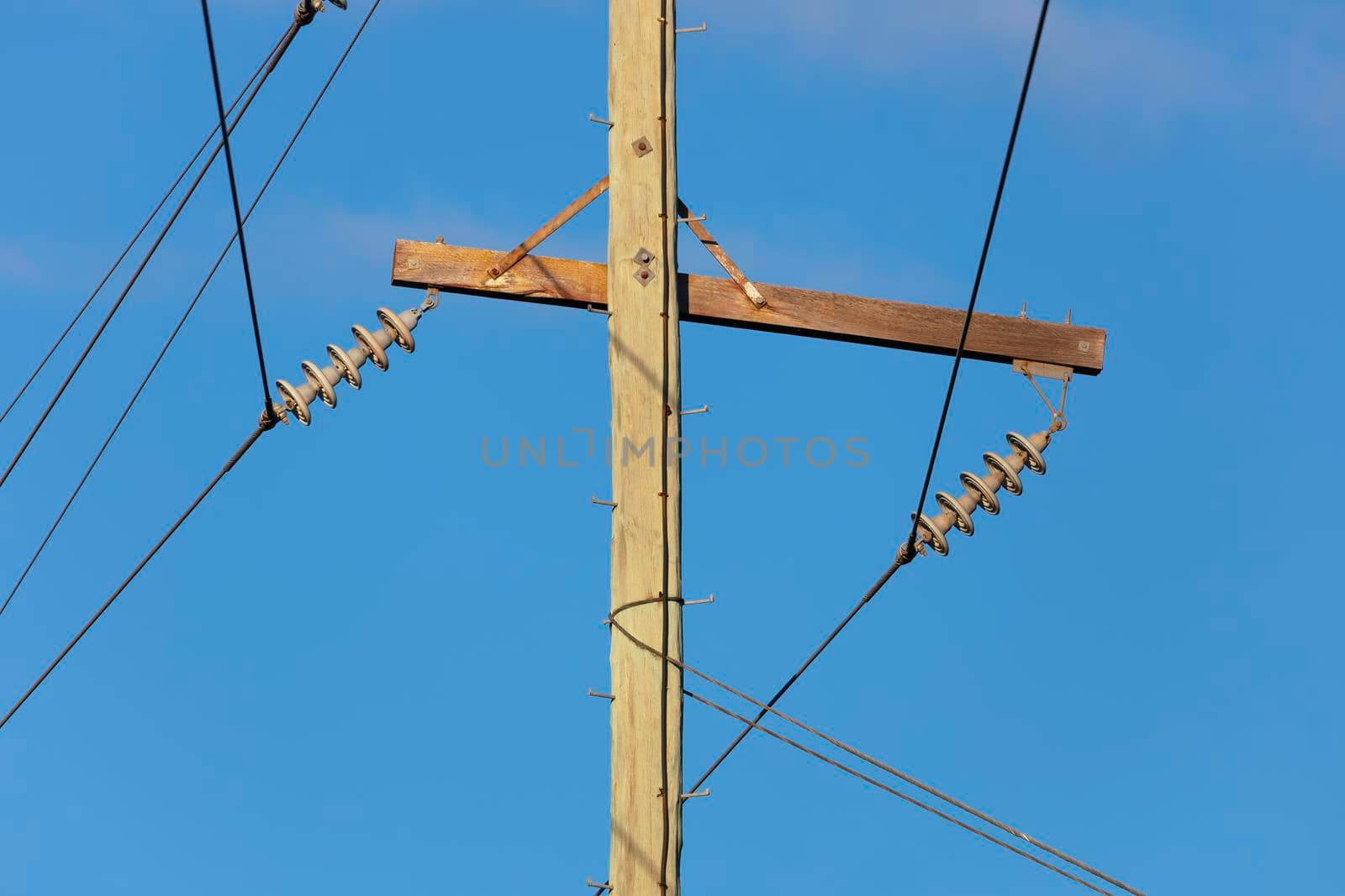 Photograph of a wooden telephone post and cables against a blue sky