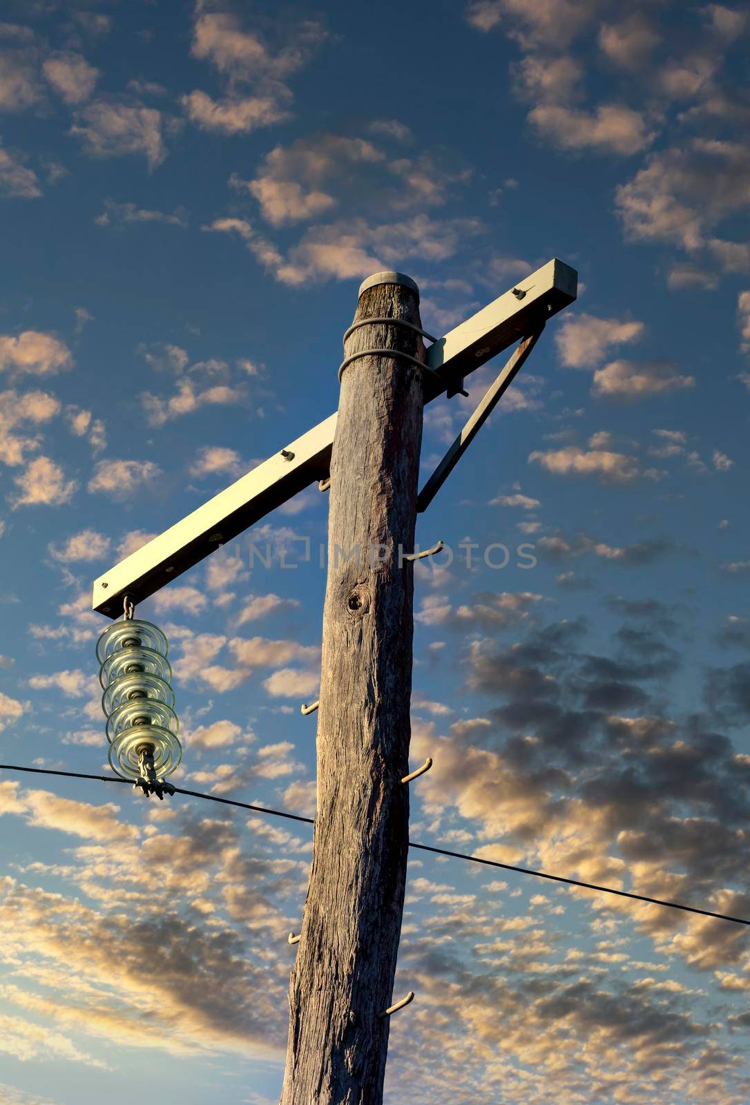 Photograph of a wooden telephone post and cables against a blue sky