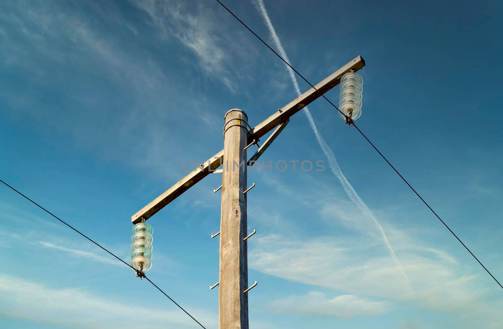 Photograph of a wooden telephone post and cables against a blue sky