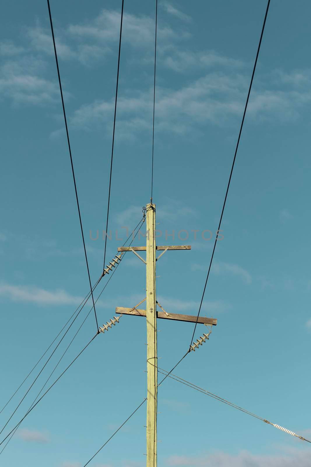 Photograph of a wooden telephone post and cables against a blue sky