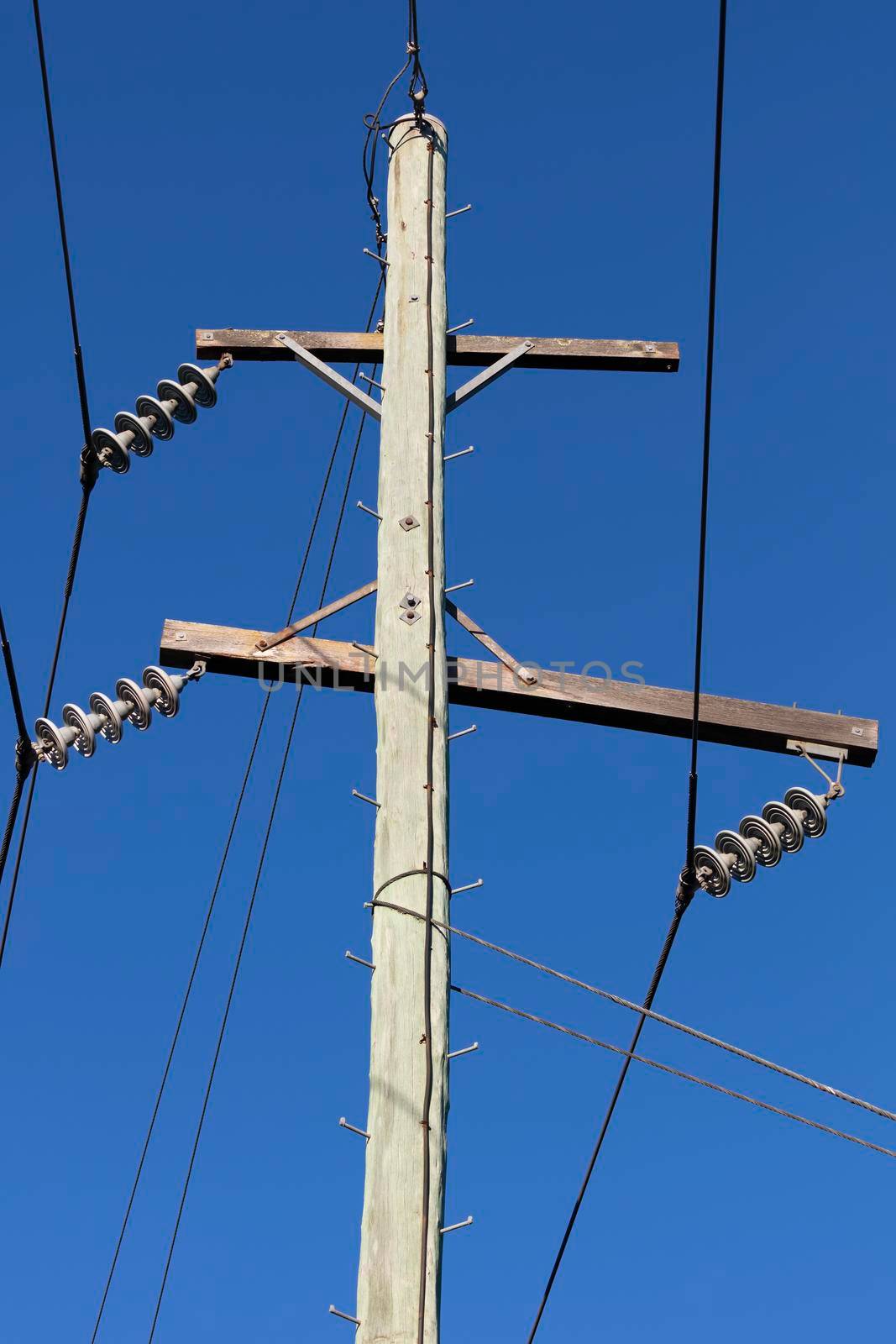 Photograph of a wooden telephone post and cables against a blue sky