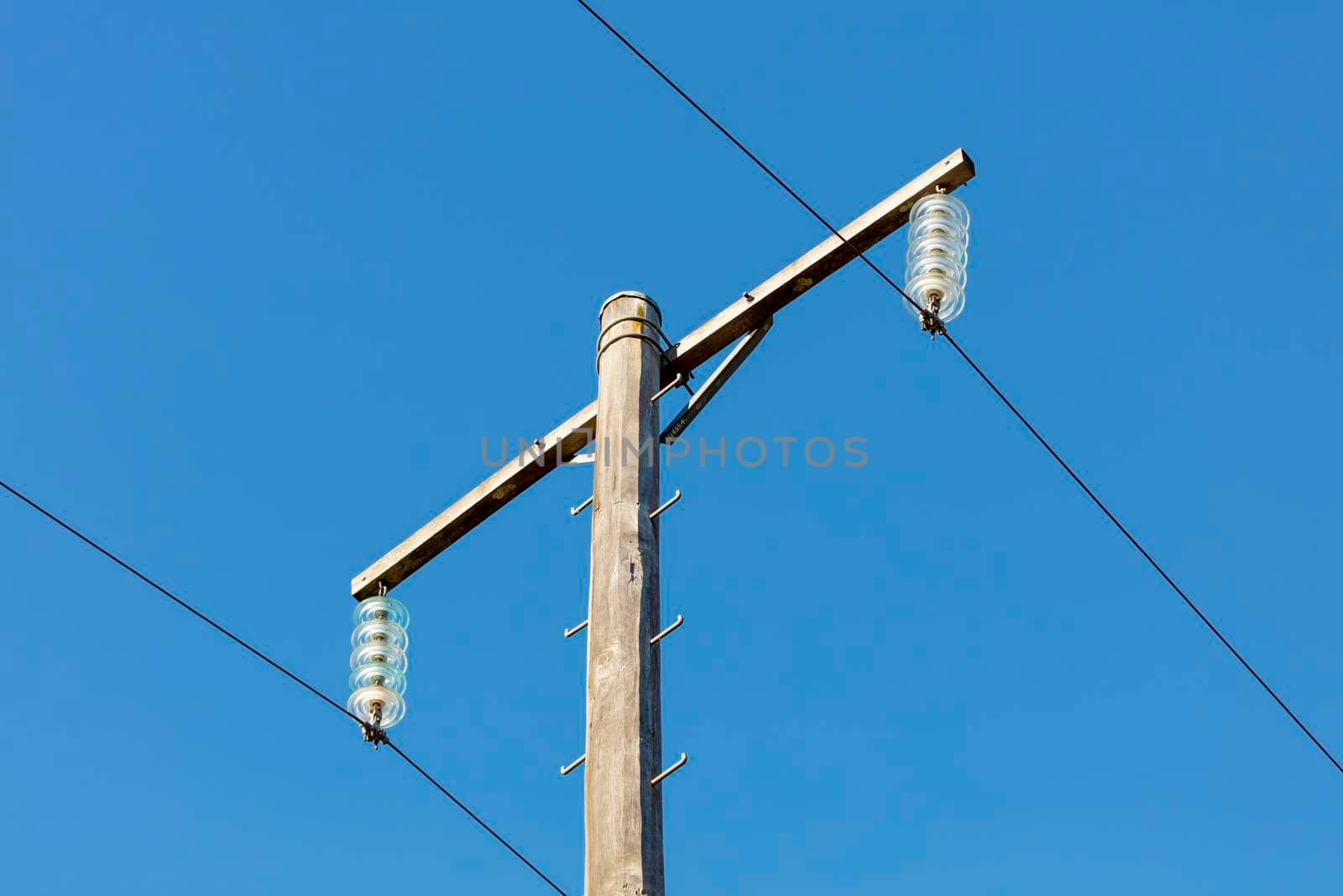 Photograph of a wooden telephone post and cables against a blue sky