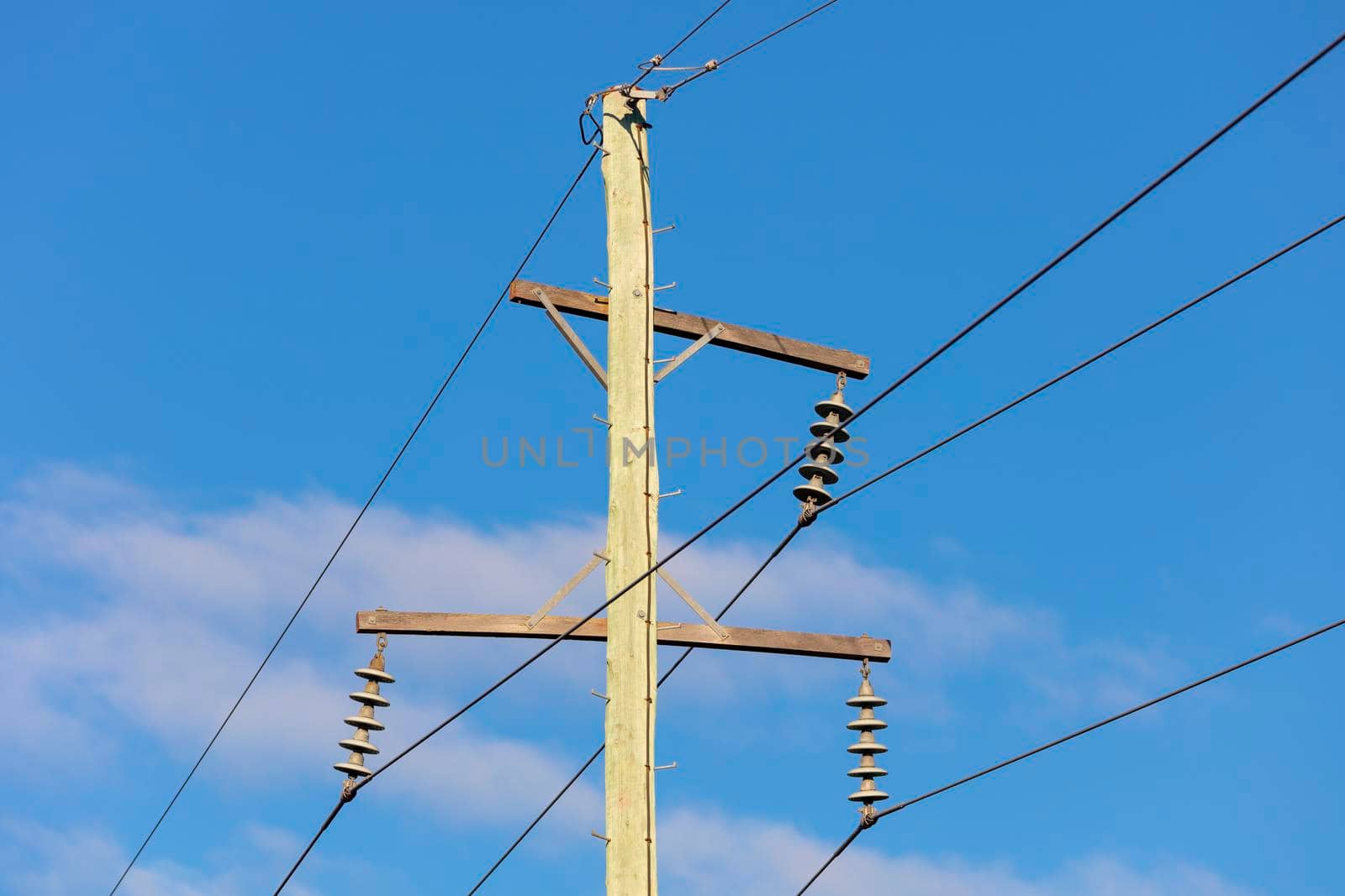 Photograph of a wooden telephone post and cables against a blue sky