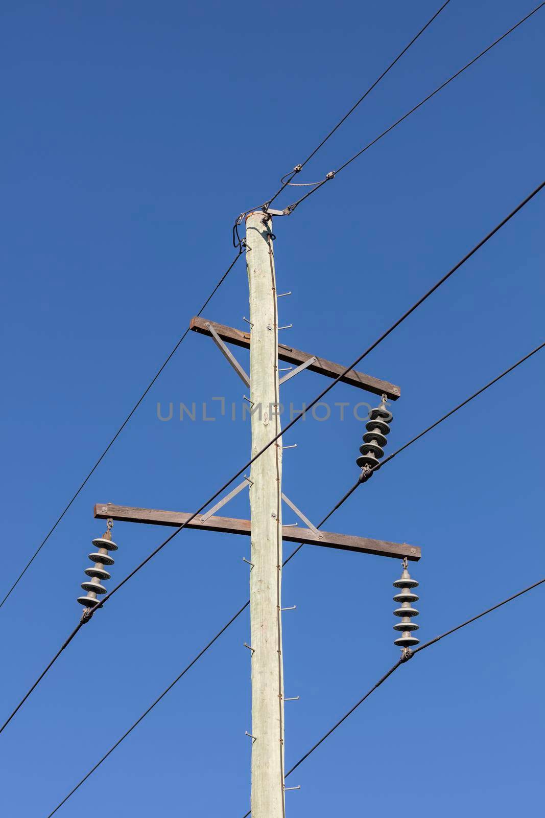 Photograph of a wooden telephone post and cables against a blue sky