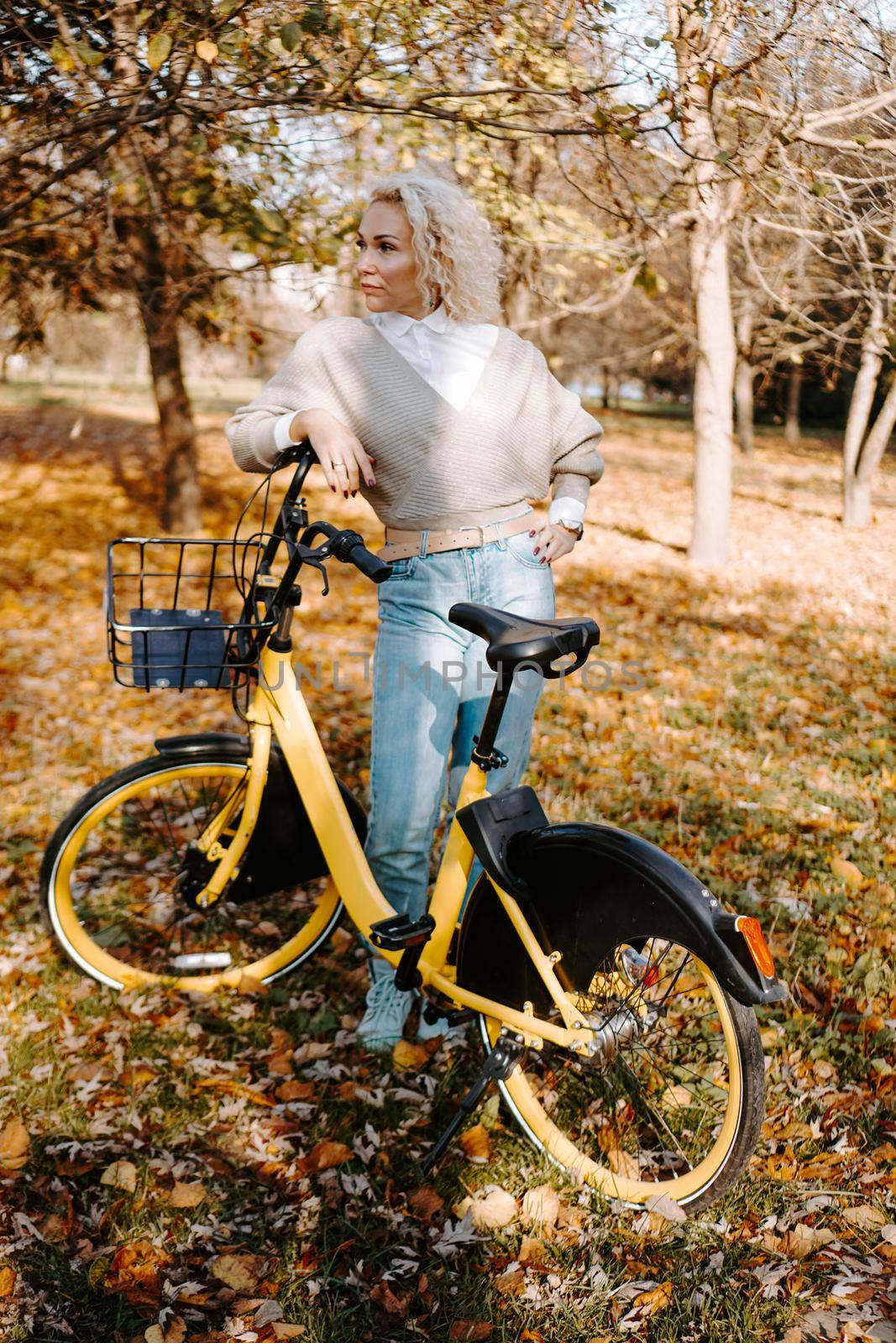 Woman on yellow Bicycle walking in the autumn Park. Middle-aged woman