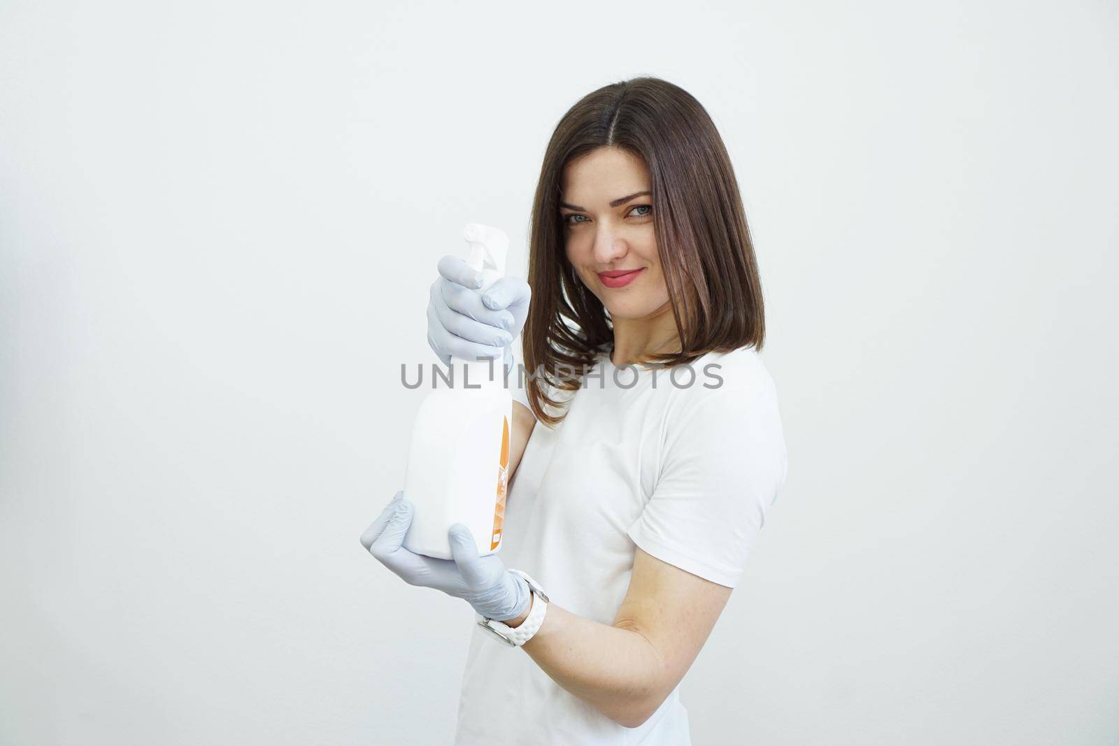 Woman holds spray bottle with antiseptic or detergent like guns. Health or cleaning concept Covid-2019, on white background