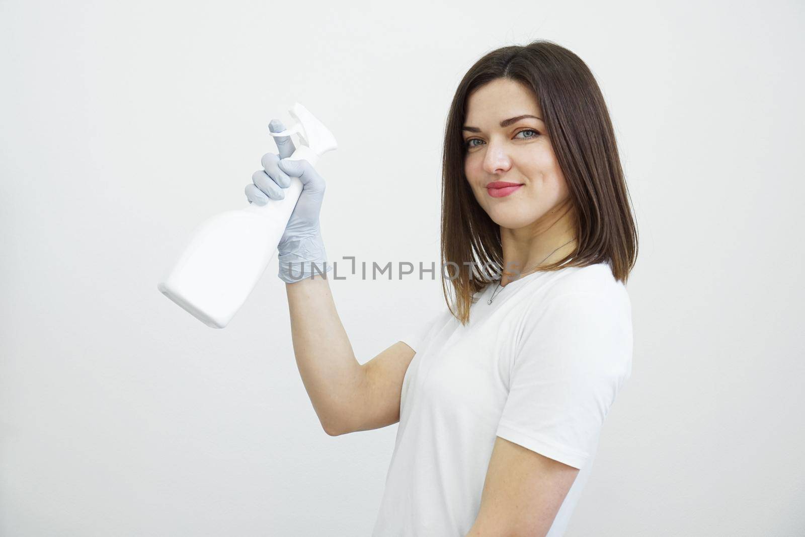 Woman holds spray bottle - antiseptic or detergent like guns. Health concept by natali_brill