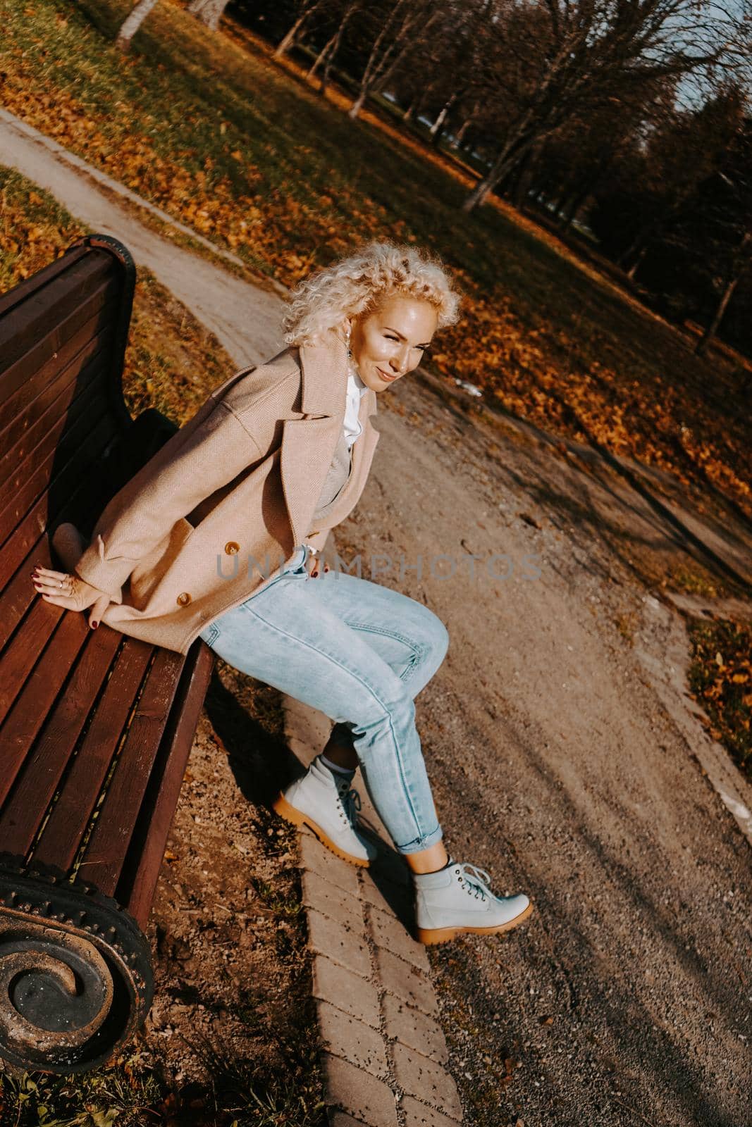 Woman sitting on the bench at autumn city park by natali_brill