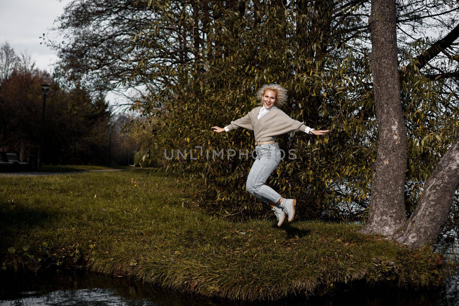 Beautiful woman in park jumping and smiling - sunny day