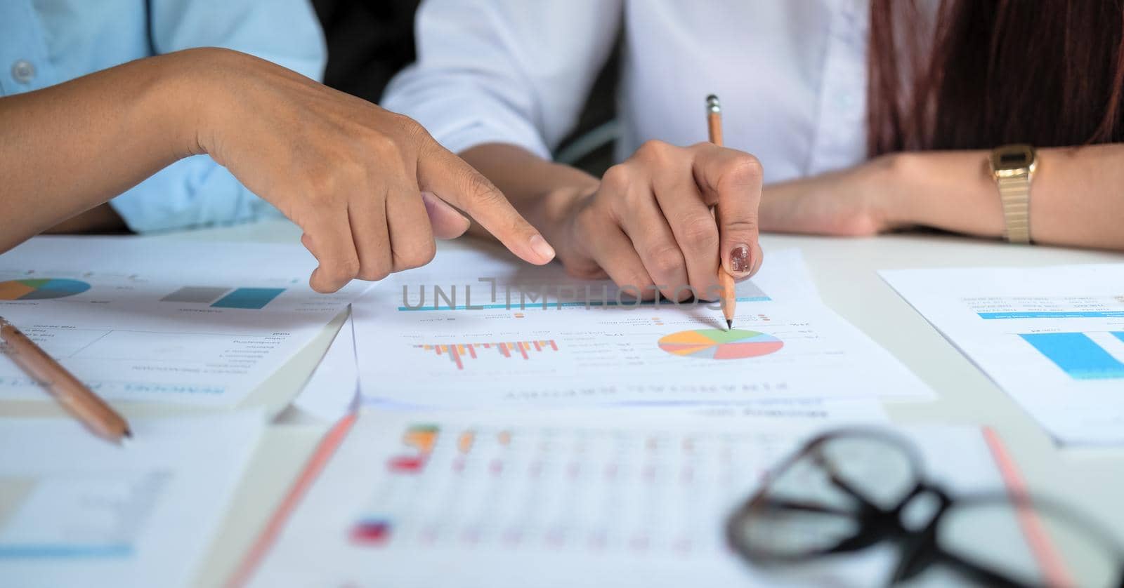 Close up hands of two colleagues discussing with document data and calculator on desk table. Close up business team analysis and strategy concept. by nateemee