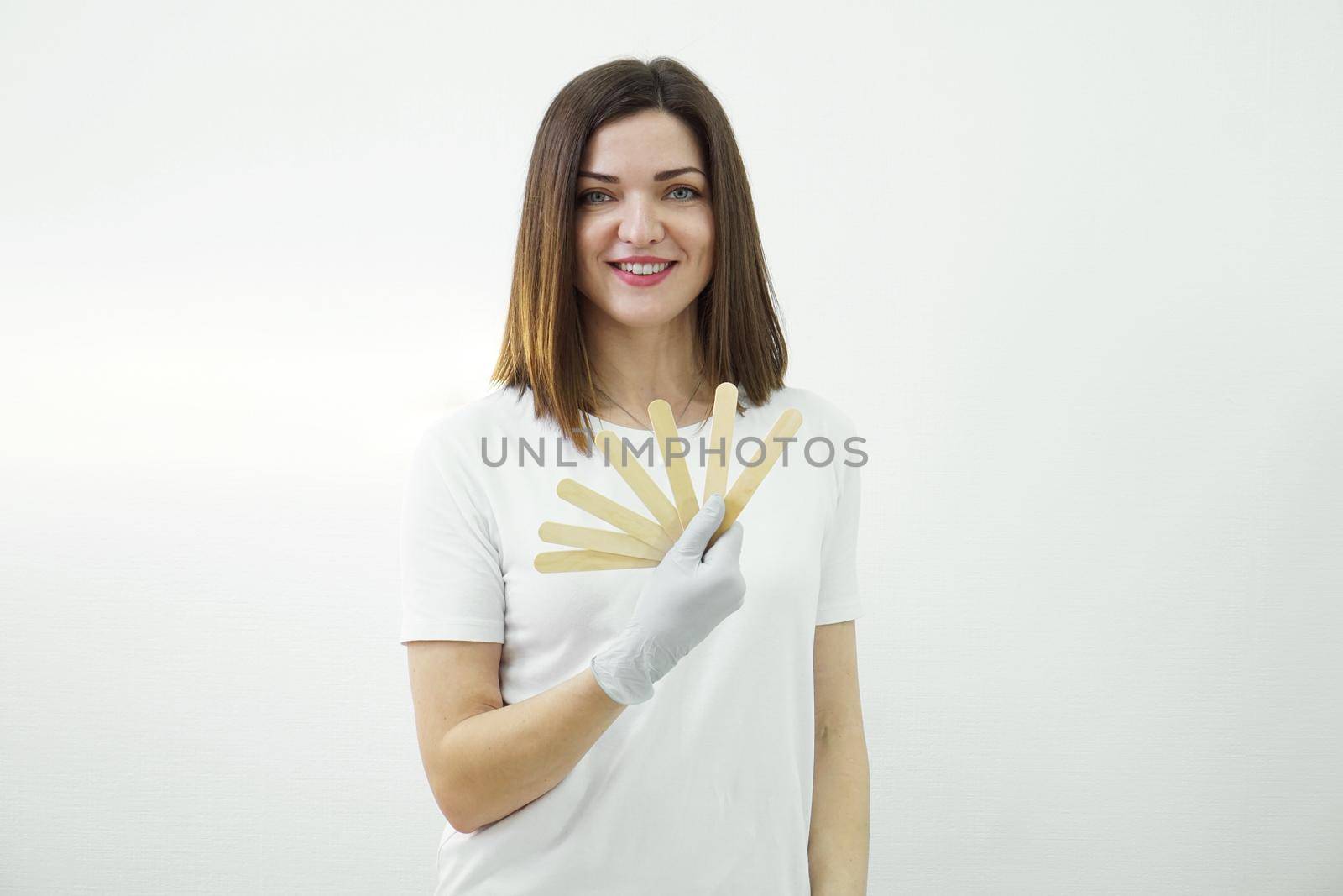 Female master of waxing or sugaring holds wooden spatula in salon