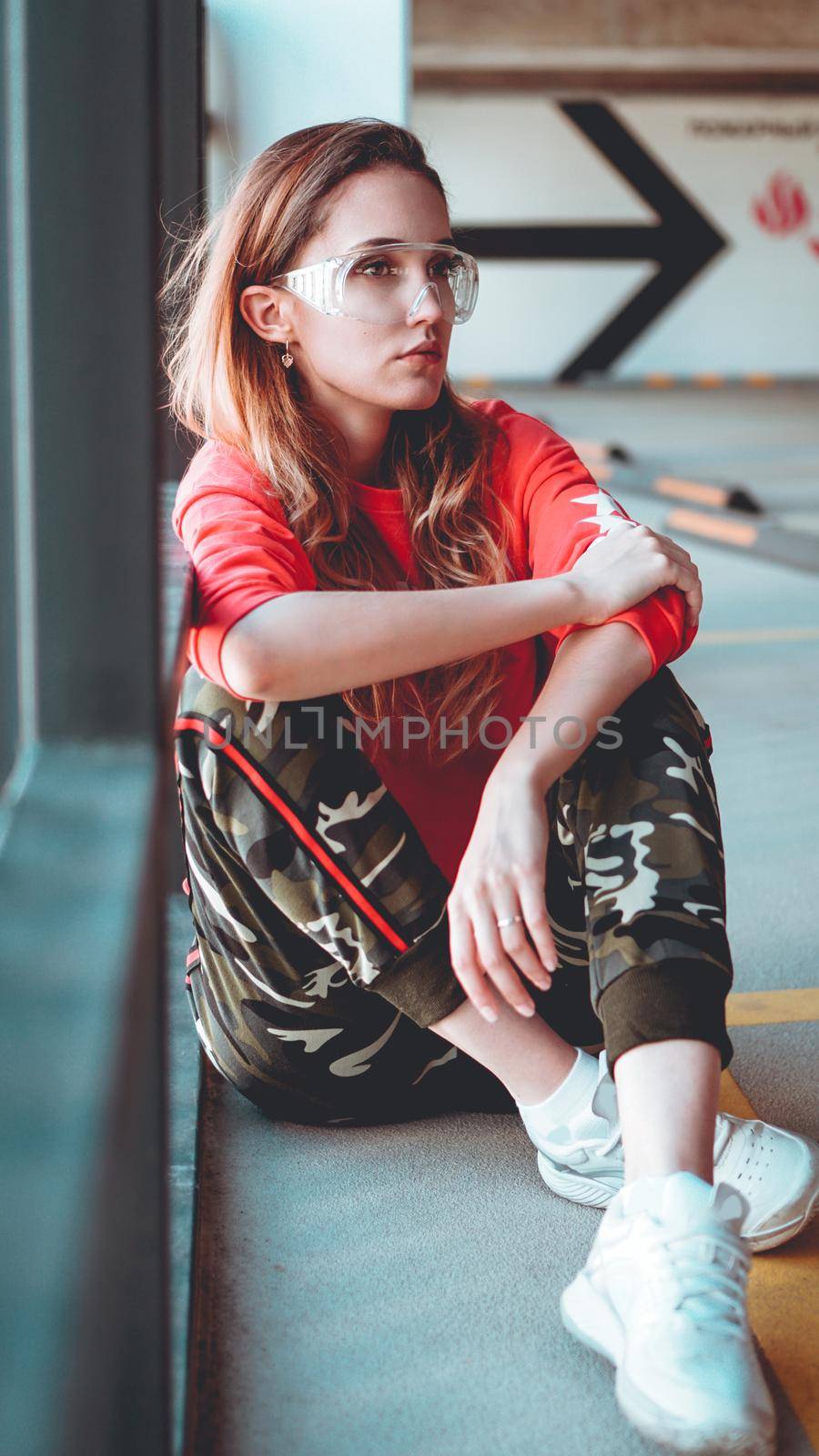 Fashion model wearing red hoodie with inscription los angeles posing at parking by natali_brill