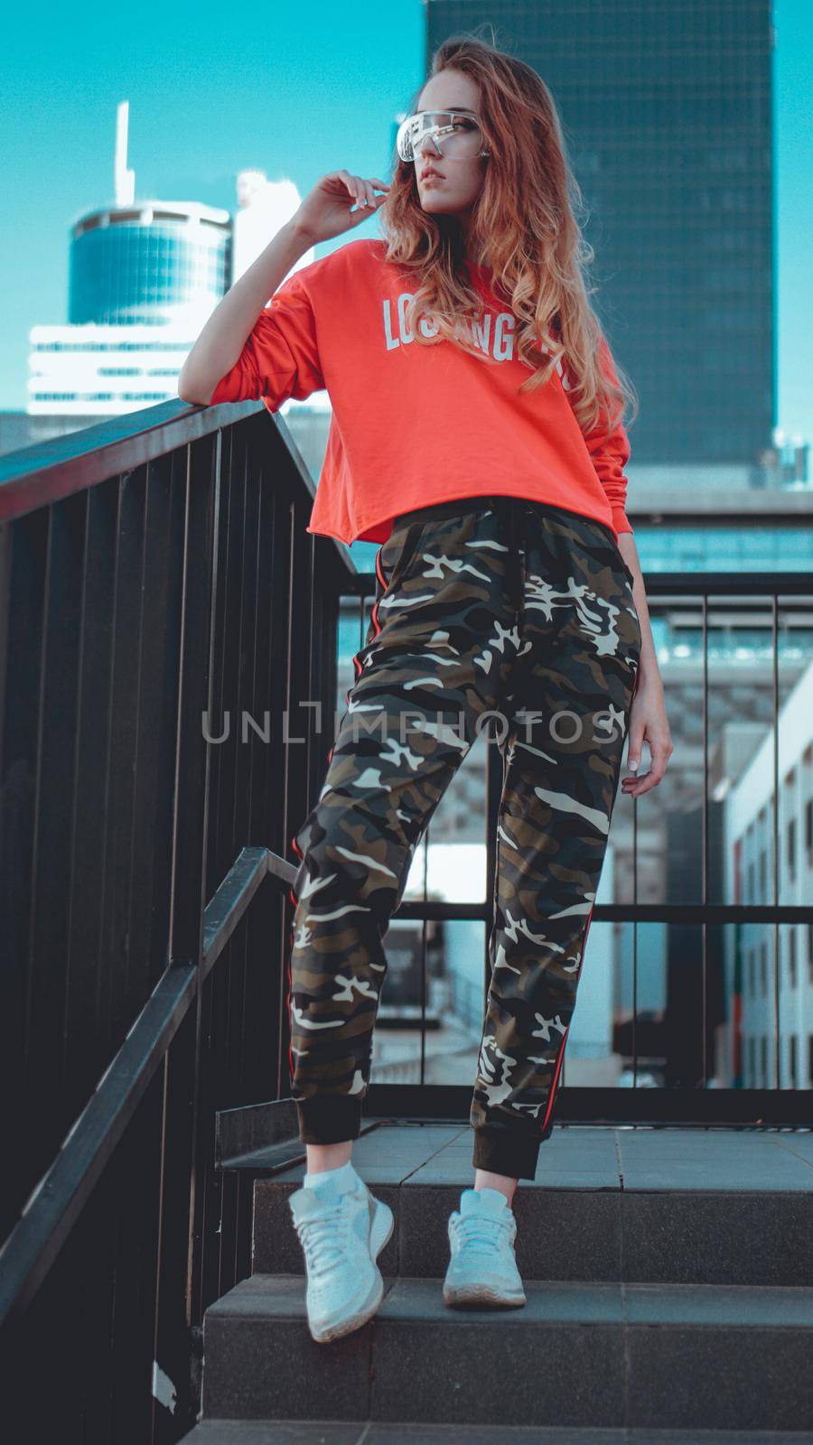 Fashion model wearing red hoodie with inscription los angeles posing at parking by natali_brill