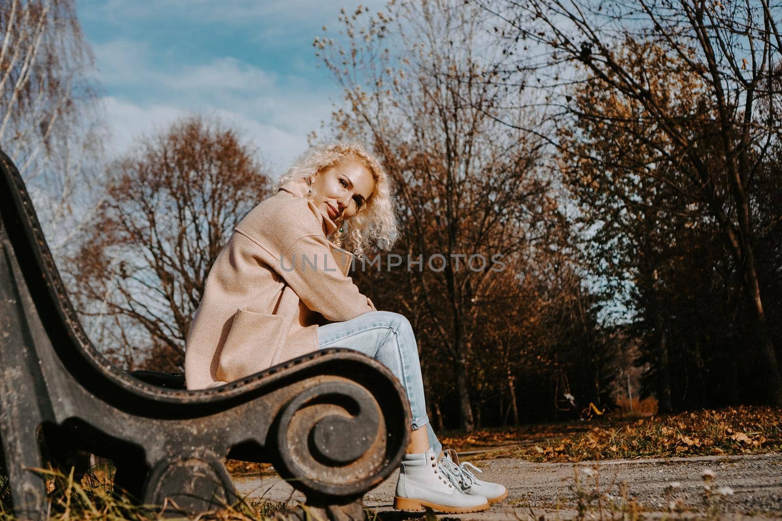 Woman sitting on the bench at autumn city park by natali_brill