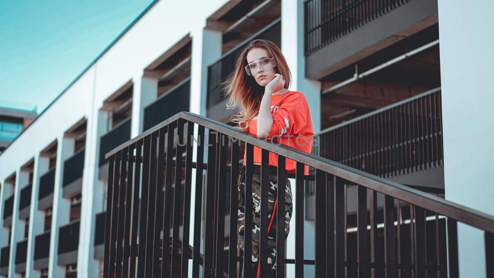 Fashion model wearing red hoodie with inscription los angeles posing at parking by natali_brill