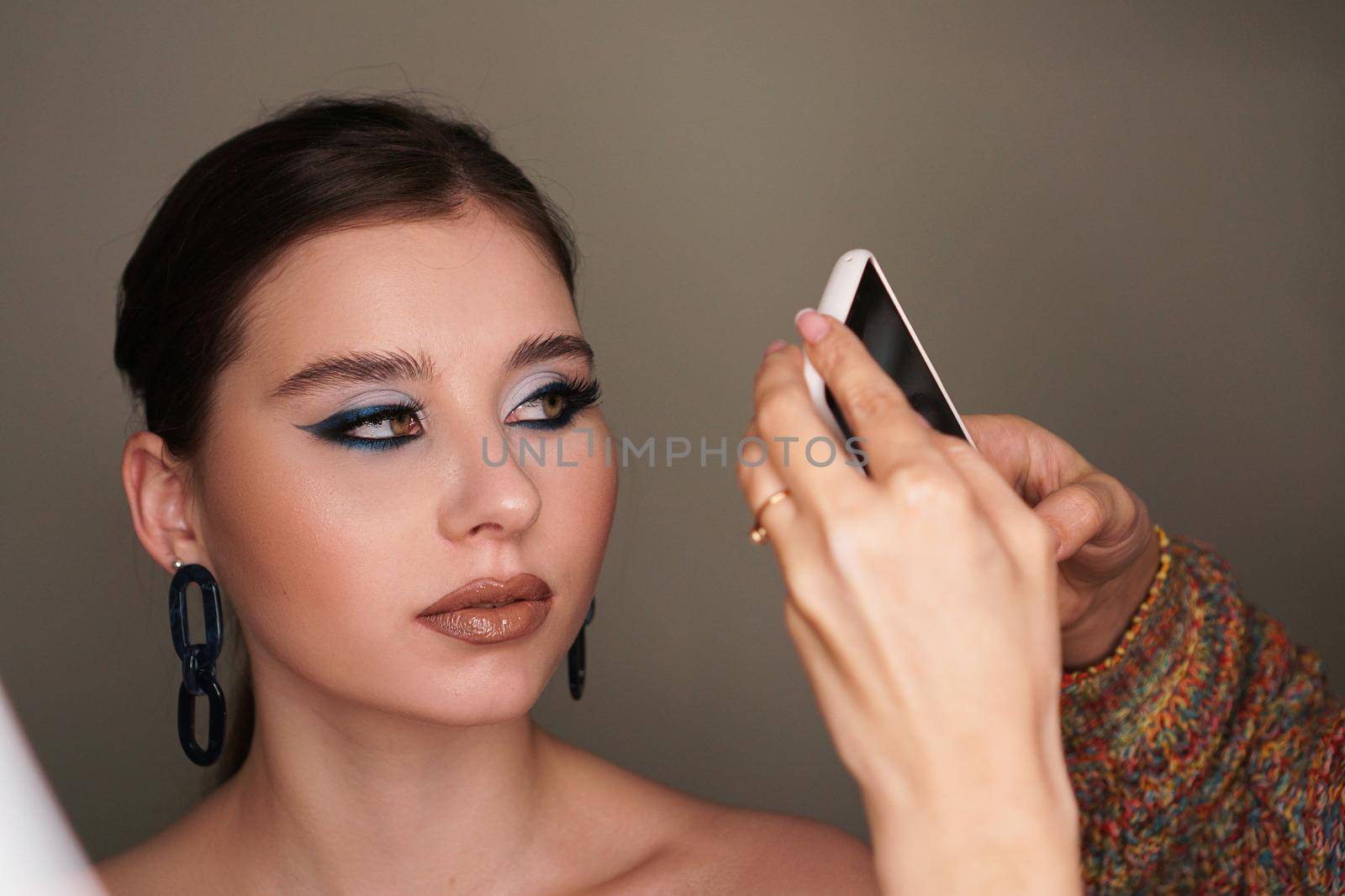 Make up artist taking mobile photo for the model with makeup by natali_brill