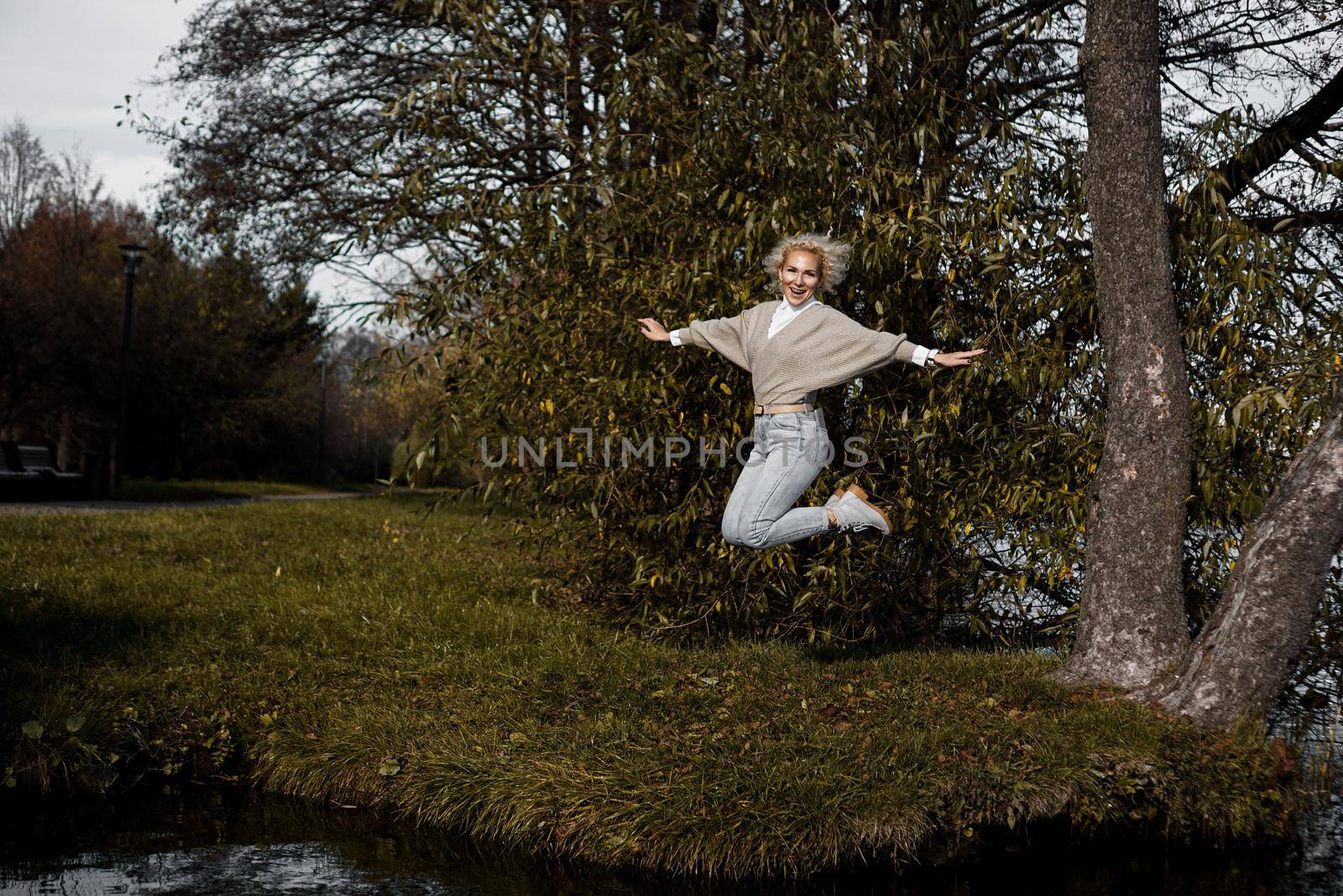 Beautiful woman in park jumping and smiling - sunny day