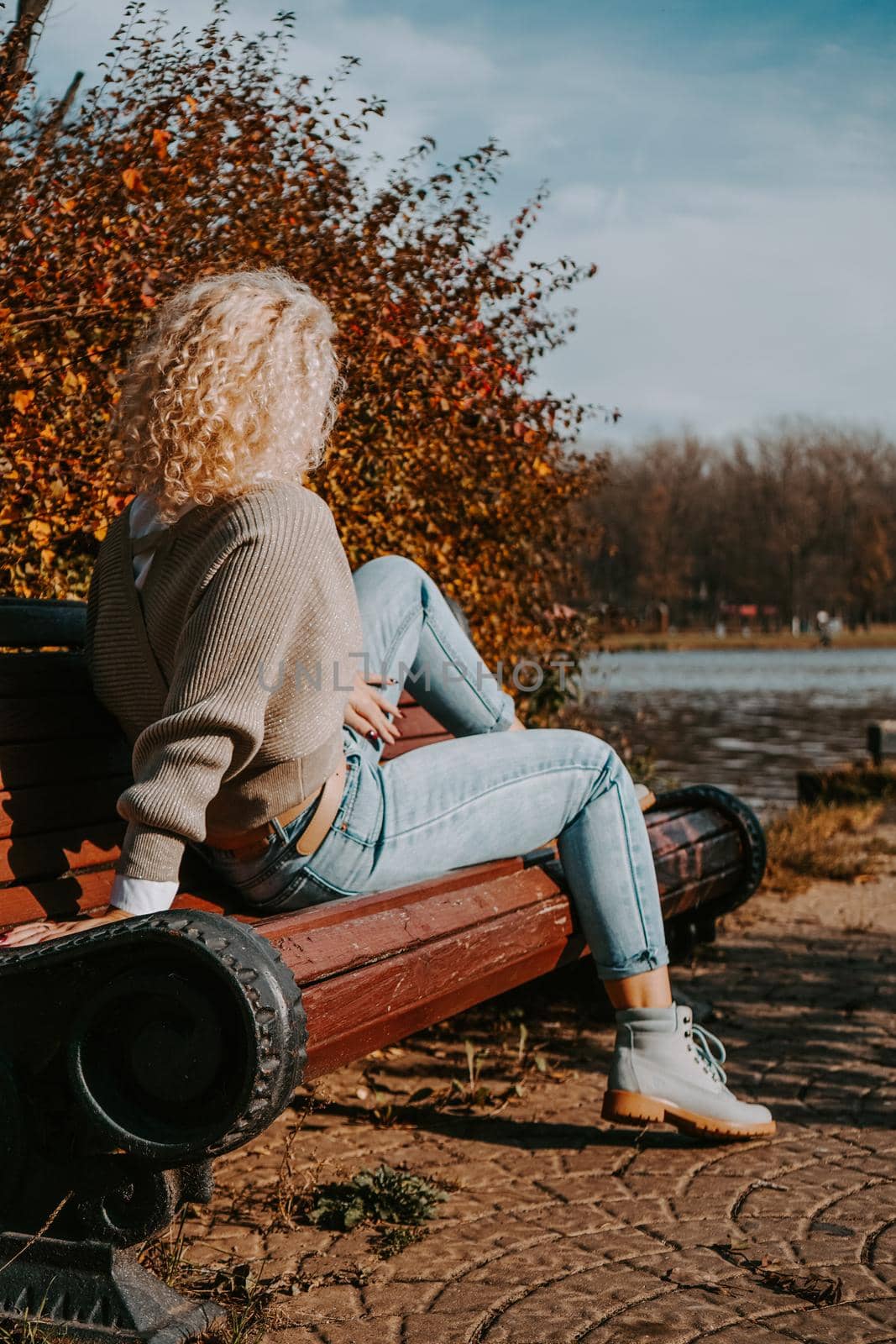 Woman sitting on the bench at autumn city park by natali_brill