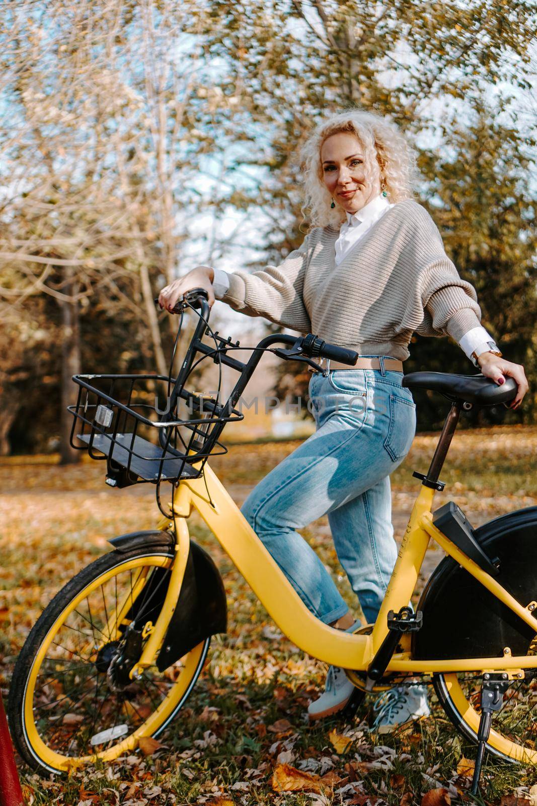 Woman on yellow Bicycle walking in the autumn Park. Middle-aged woman