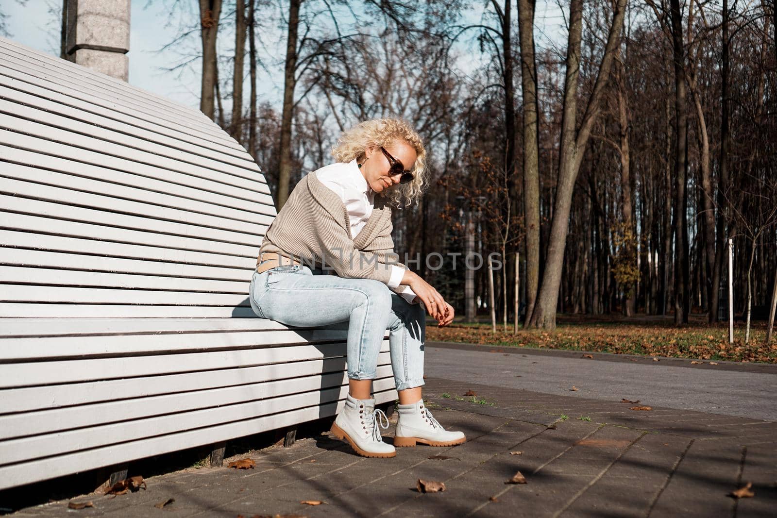Pretty woman in sunglasses on bench at autumn park alone, lifestyle people concept