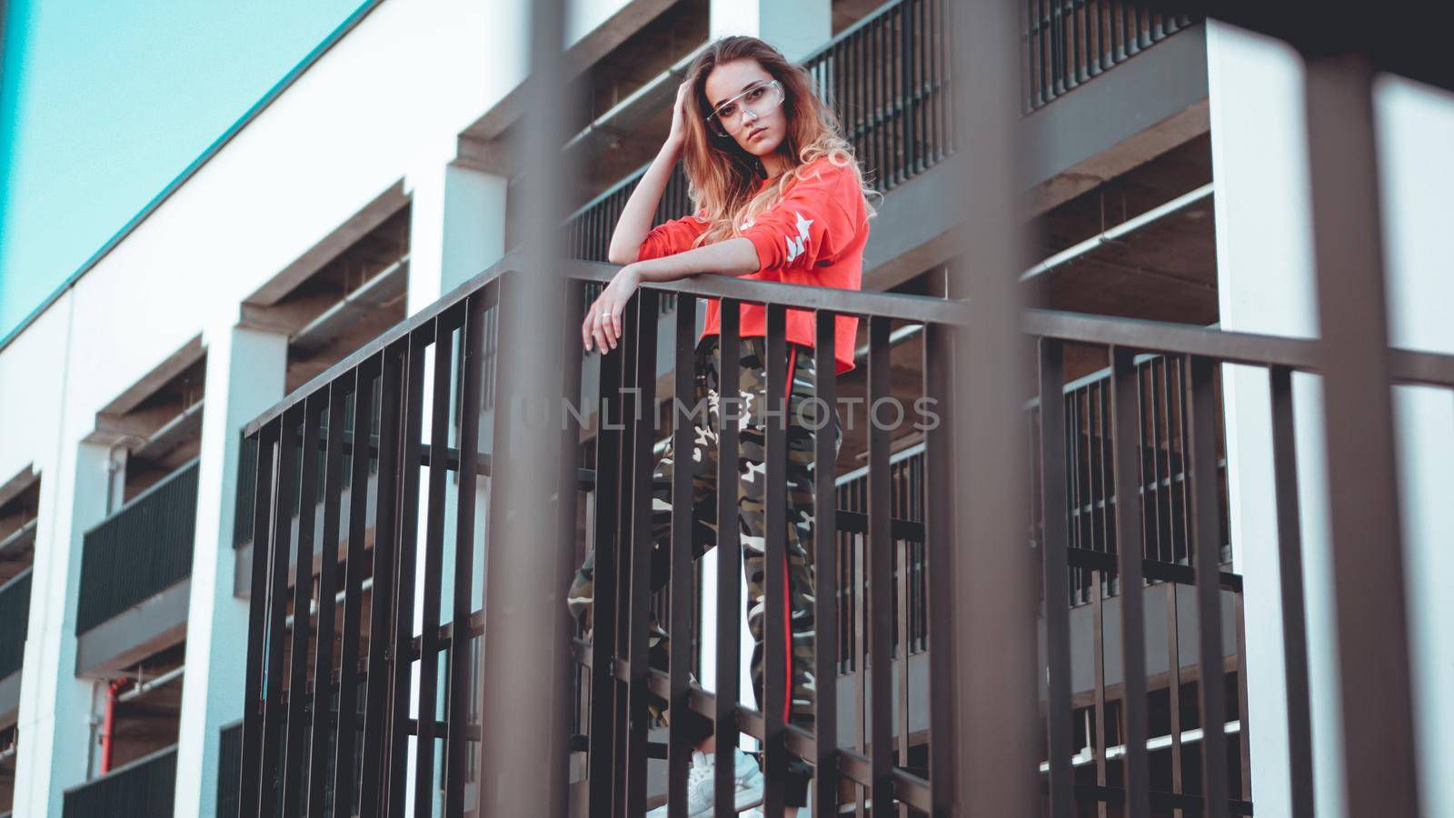 Fashion model wearing red hoodie with the inscription los angeles posing in the city at parking. Fashion urban outfit. Casual everyday clothing style