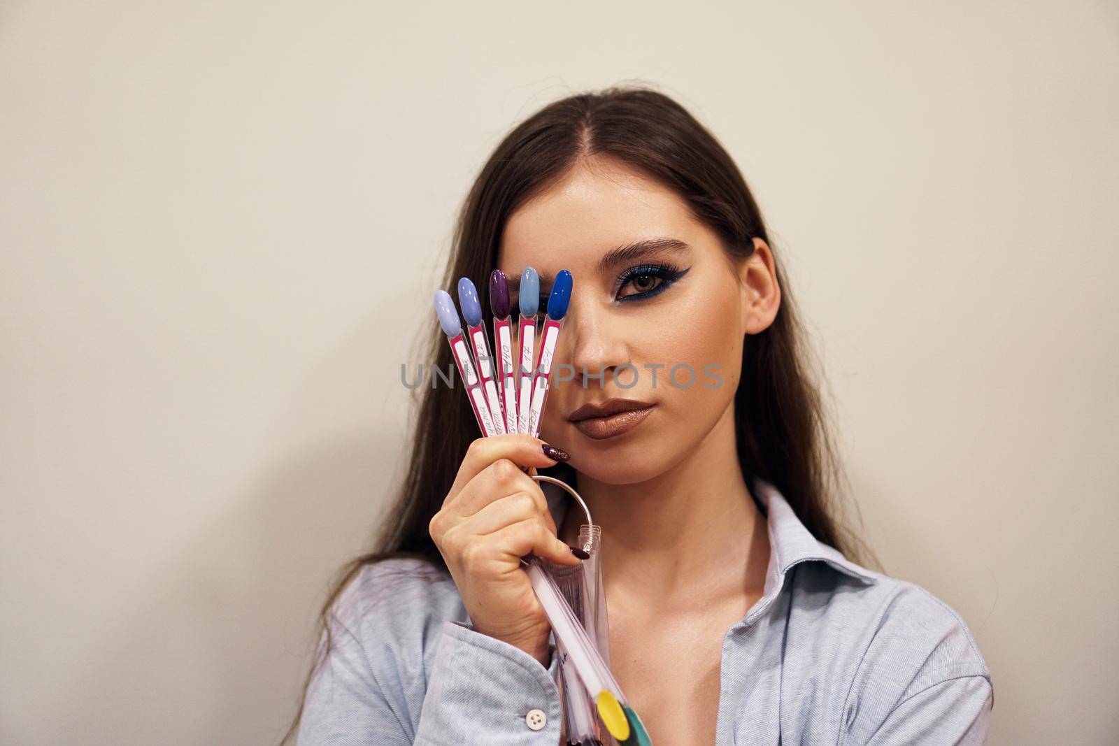 Beautiful girl with blue makeup covers her face with a palette with nails by natali_brill