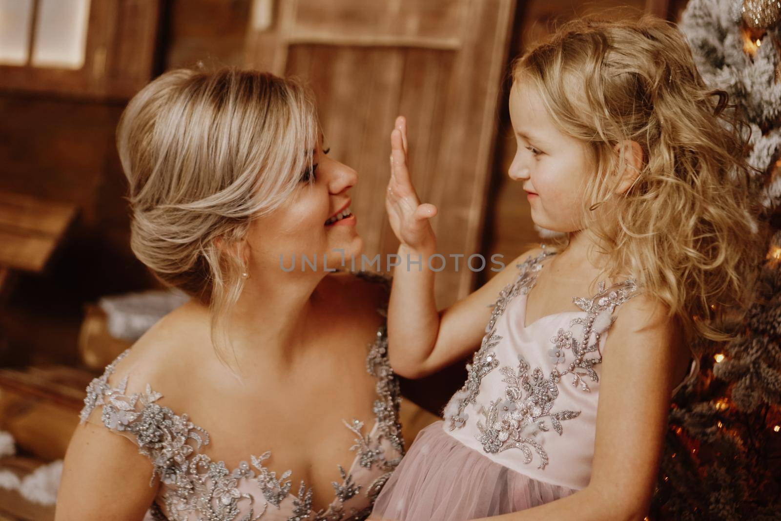 Happy Mother and her daughter in pink dresses near the Christmas decorations