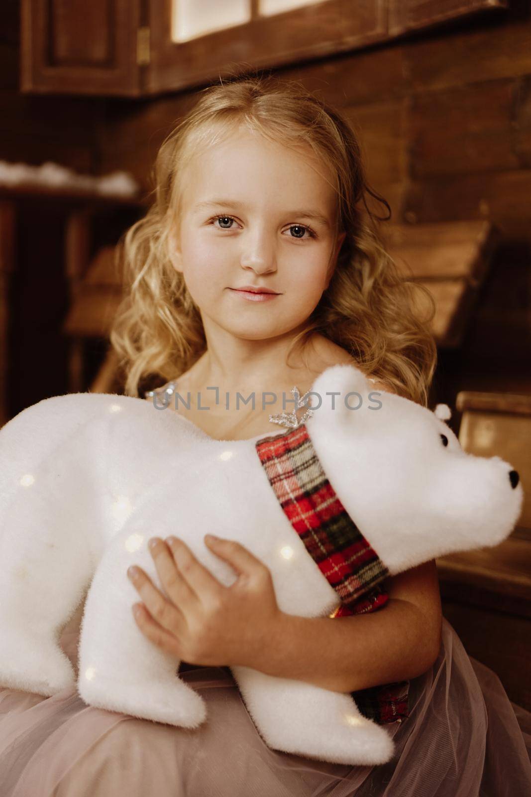 Little baby girl toddler sitting with white polar teddy bear happy on wooden background