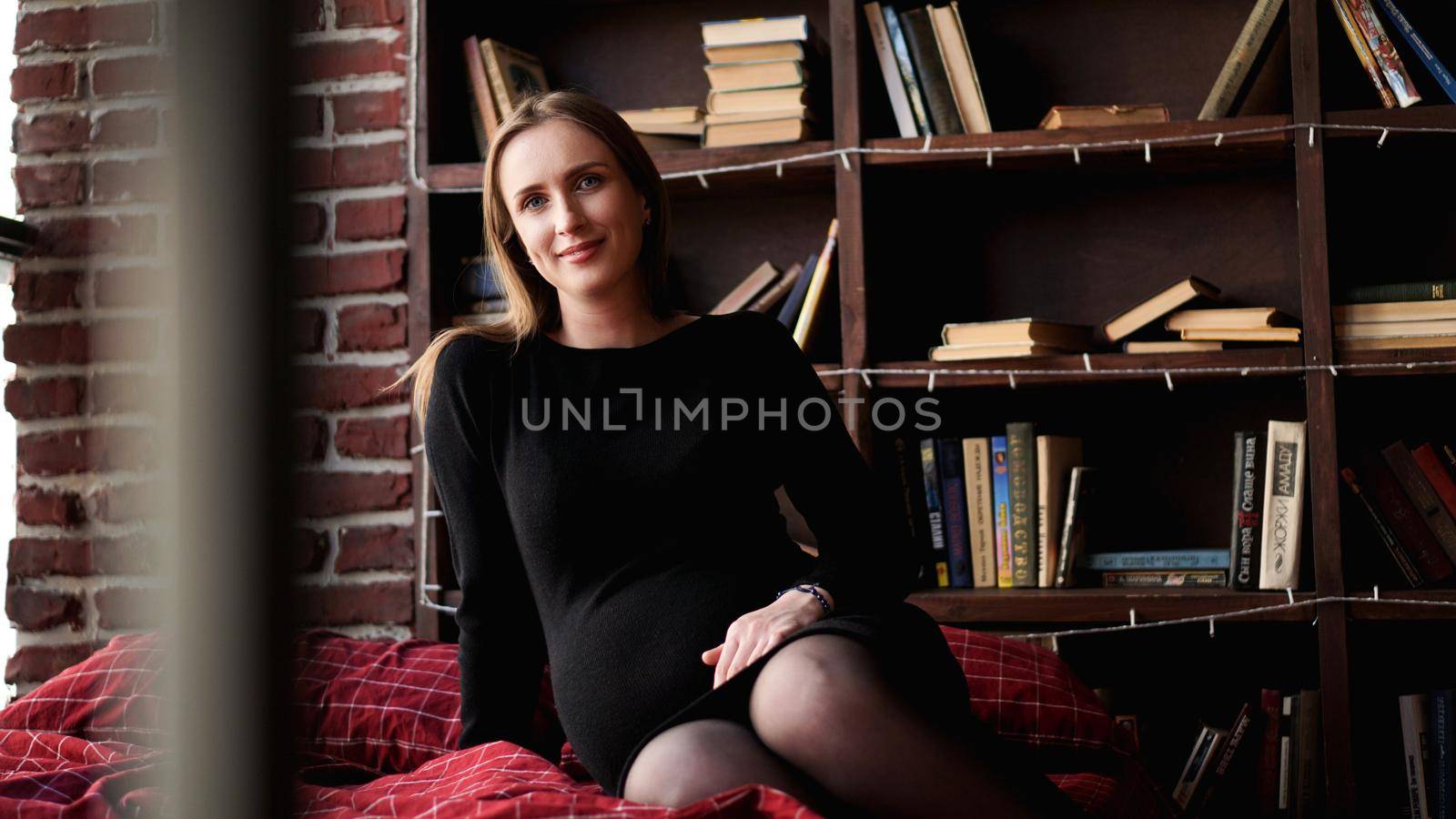 Young pretty pregnant woman in black dress in studio - loft interior