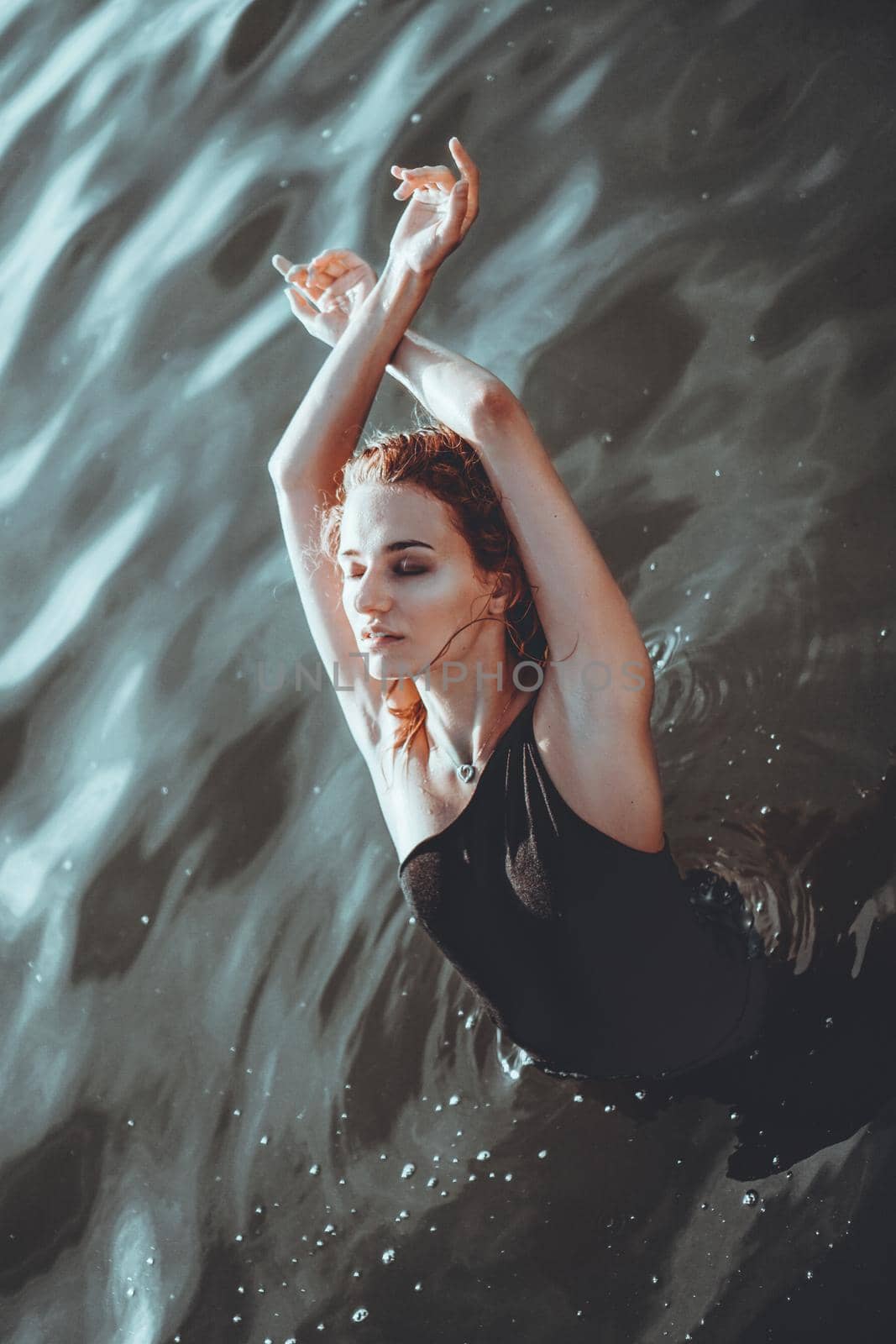 Young beautiful woman standing in the water. Black swimsuit. Vintage style