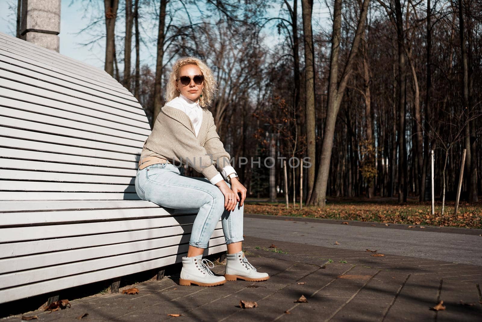 Pretty woman in sunglasses on bench at autumn park alone, lifestyle people concept