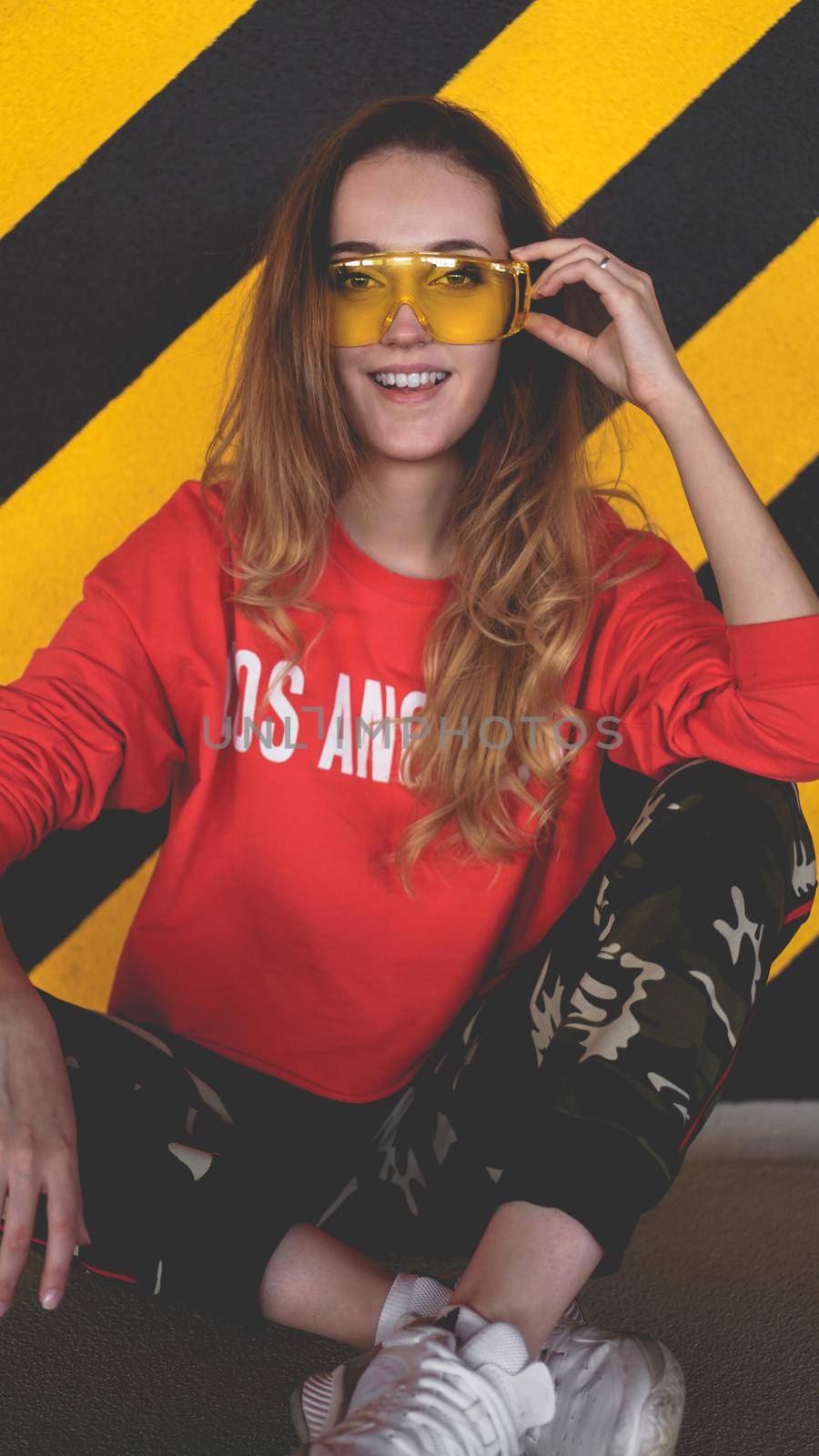 Fashion model wearing red hoodie with inscription los angeles posing at parking by natali_brill