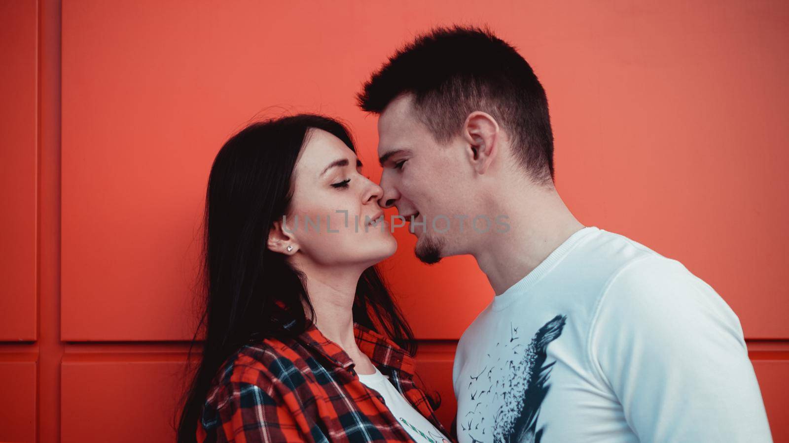 Couple kissing against isolated red wall in the city - red background, love concept