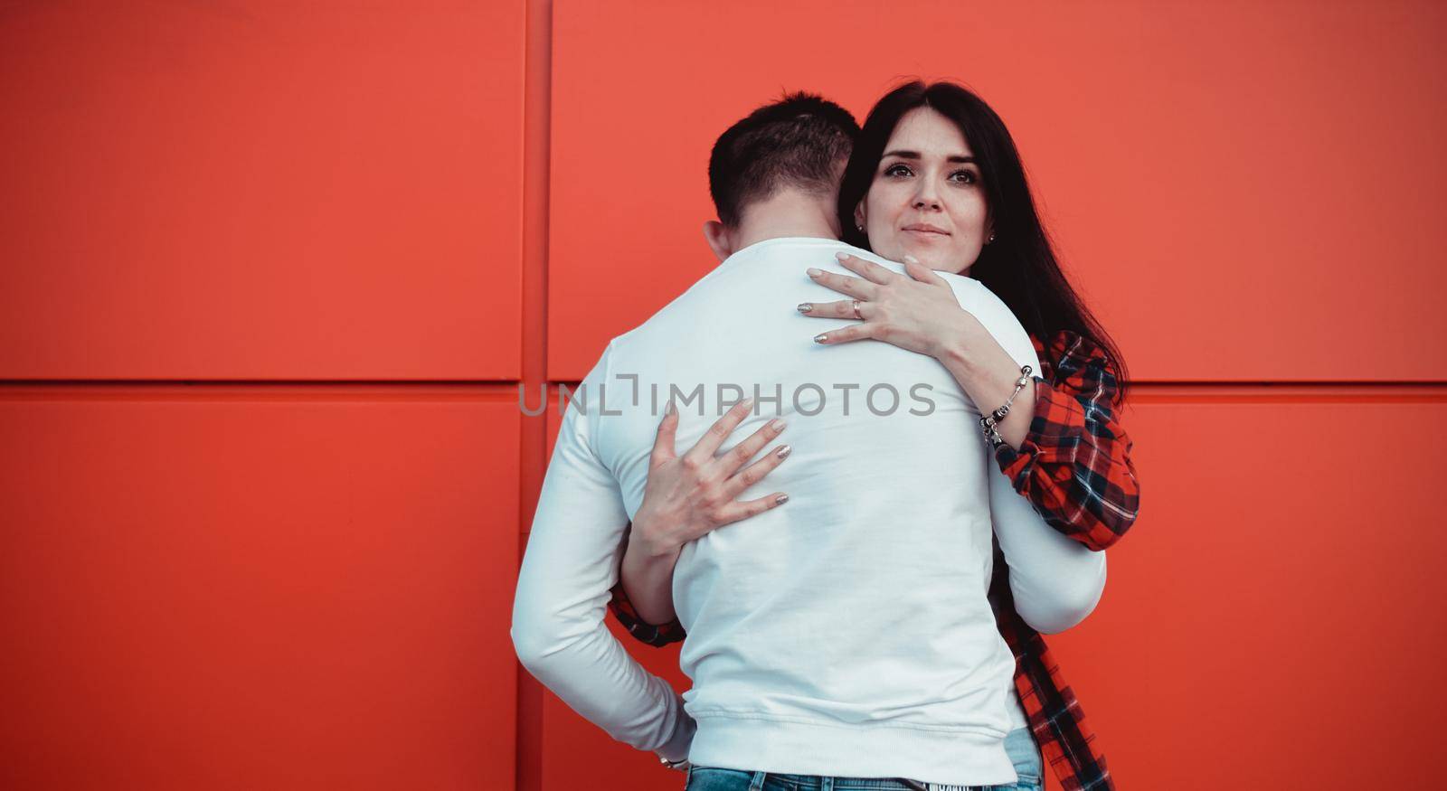 Couple dating and hugging in love in an urban in a sunny day - red background