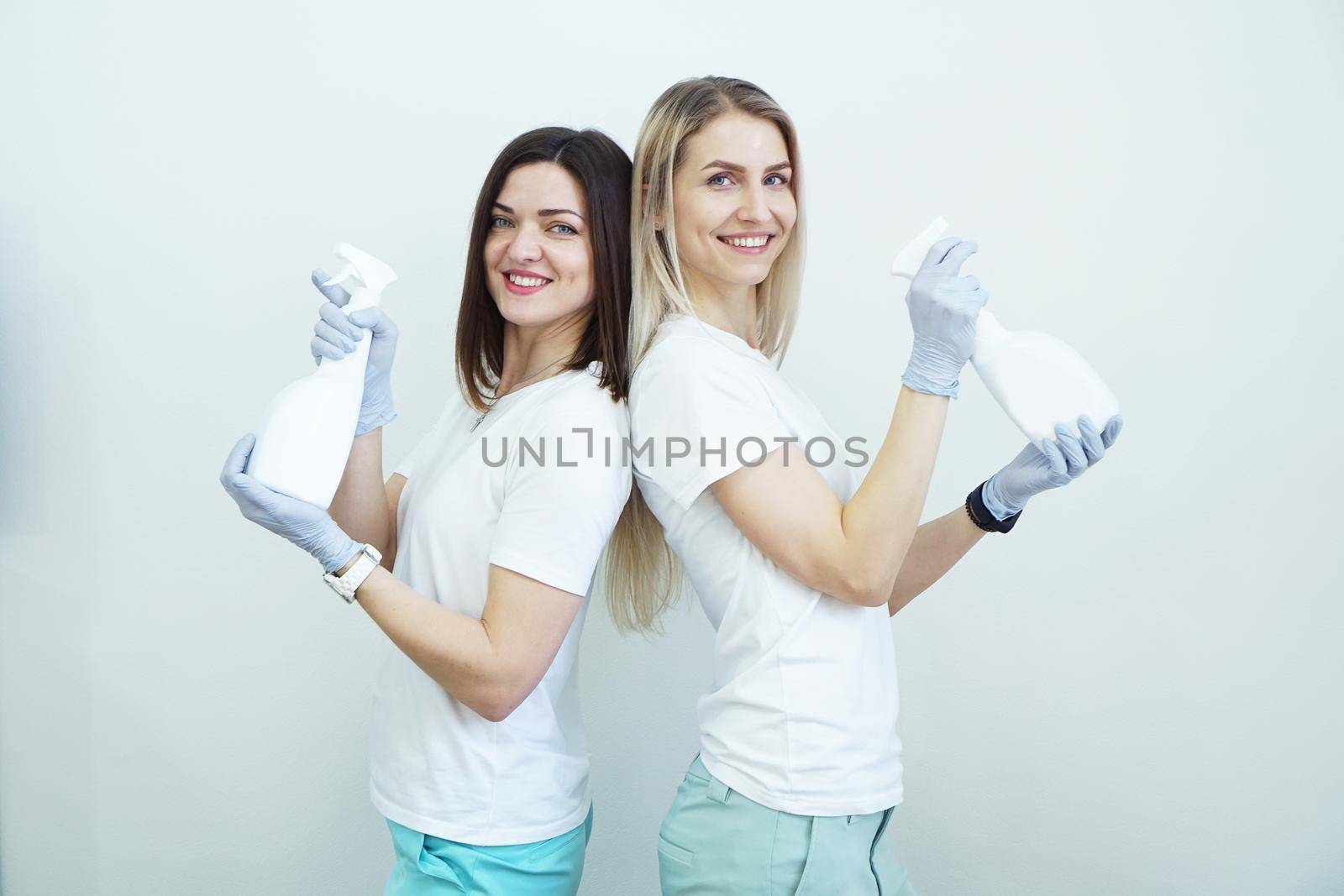 Two women hold spray bottle - antiseptic or detergent like guns. Health concept by natali_brill