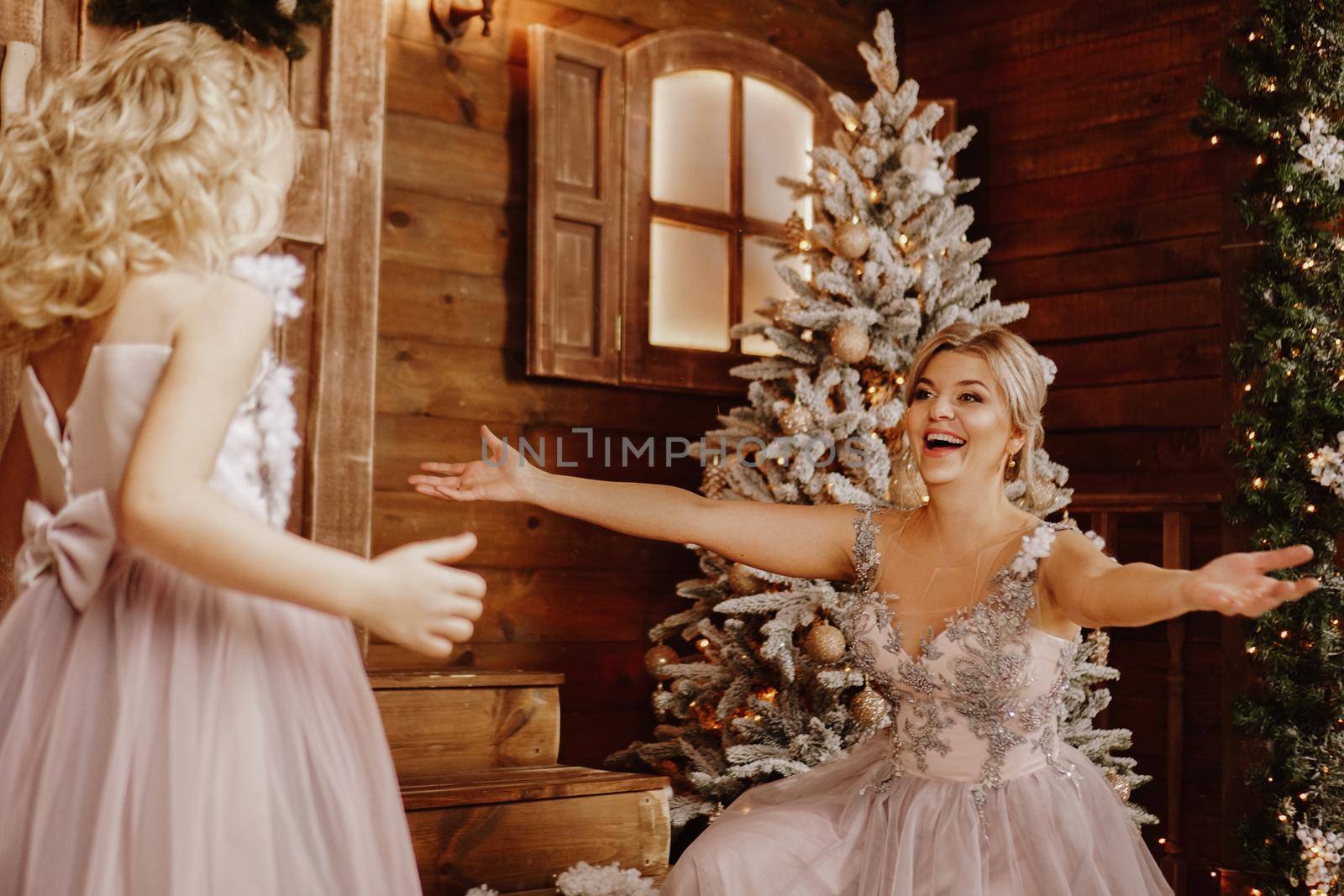 Mother and her daughter in pink dresses near the Christmas decorations by natali_brill