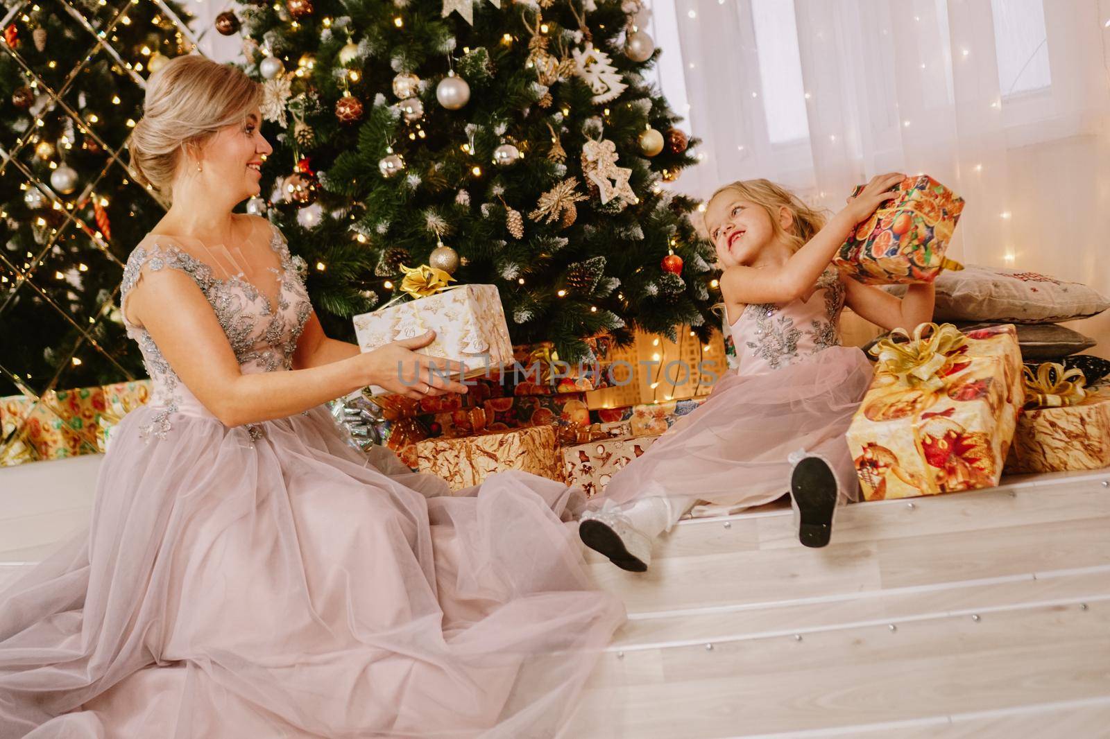 Christmas concept. Happy mother and daughter in christmas room. Give gifts by natali_brill