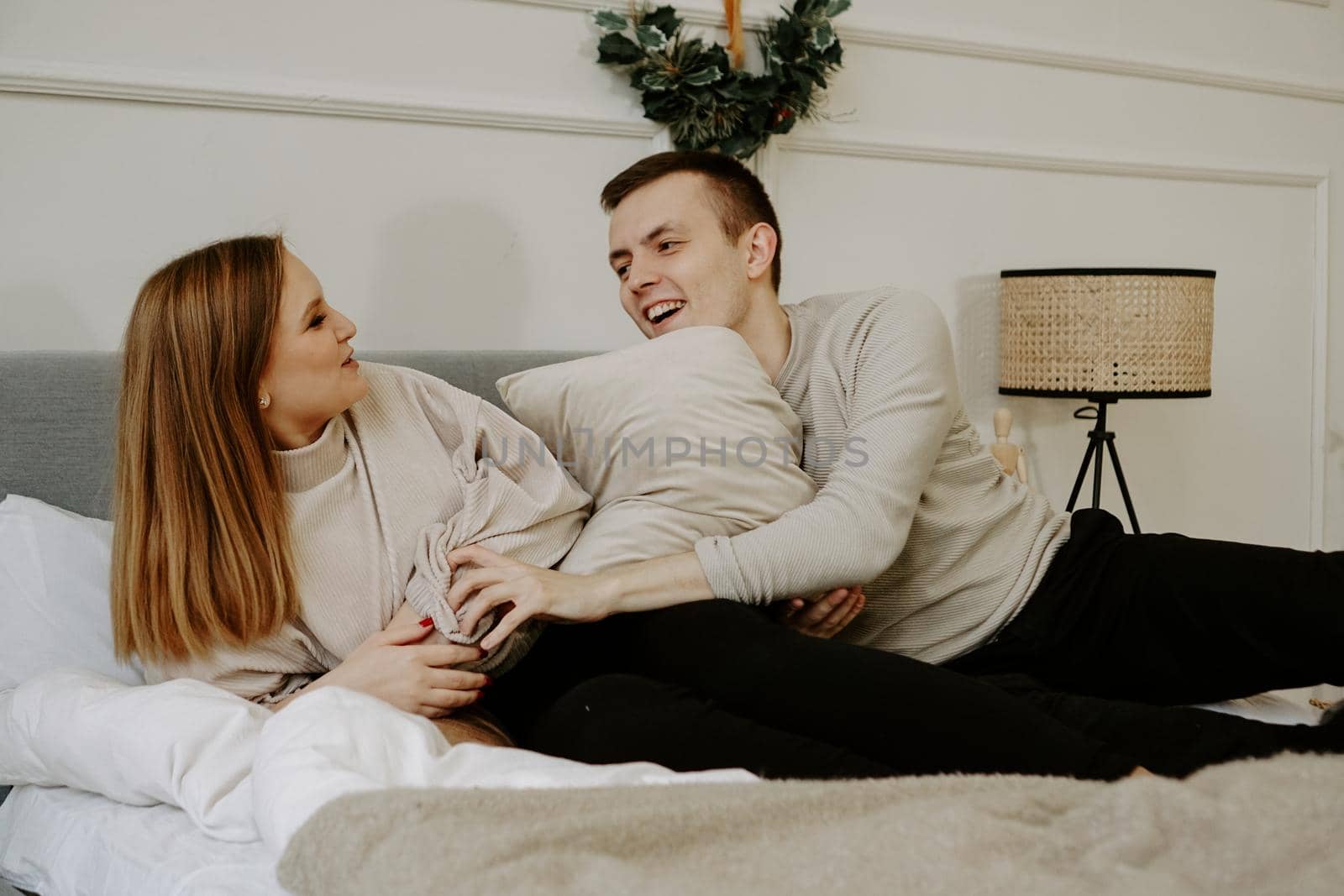 Young couple in love is lying in bed, smiling and fooling around by natali_brill