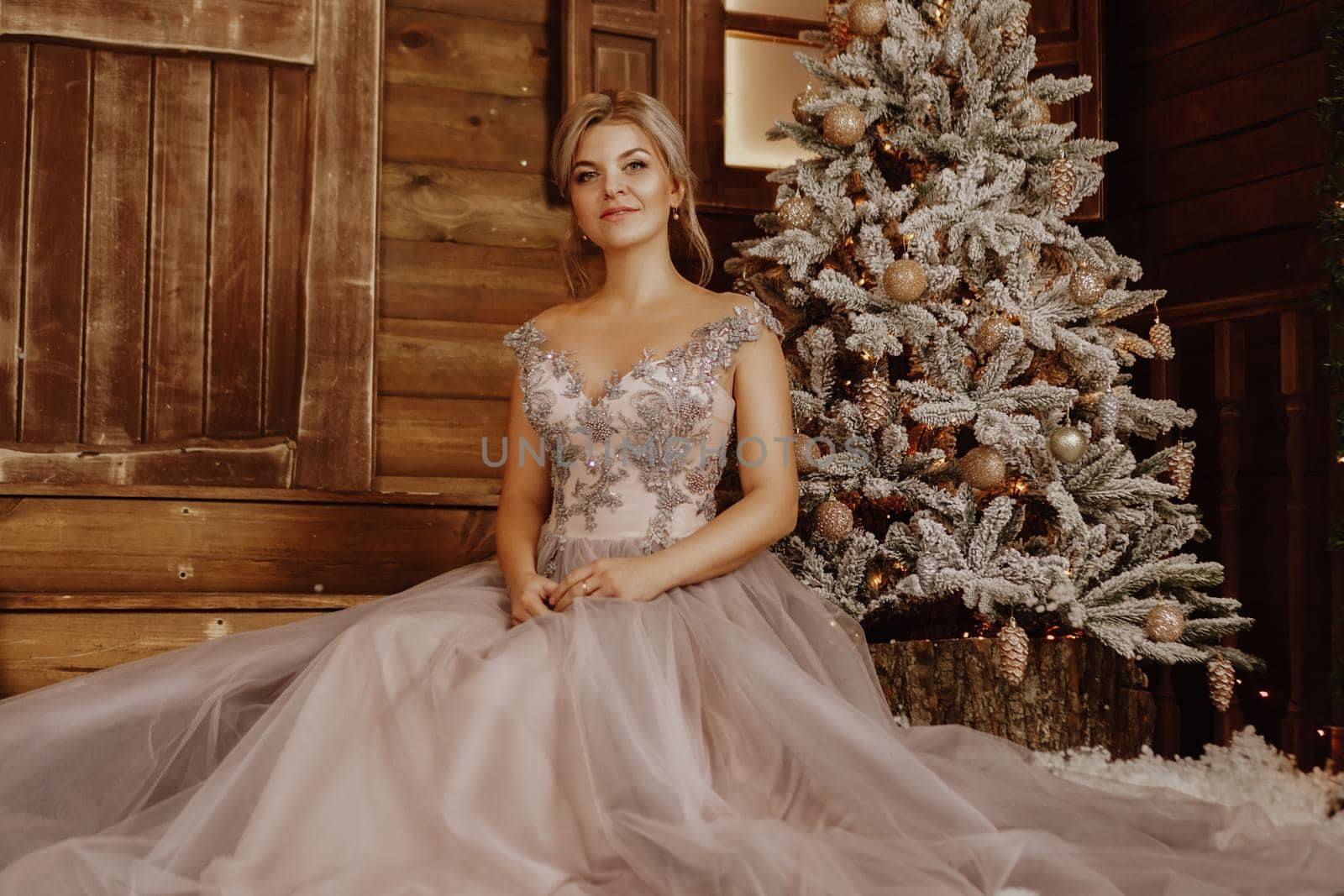 Christmas, winter holidays concept. Beautiful woman in evening long dress posing in luxurious apartments decorated for Christmas. Beauty, fashion.