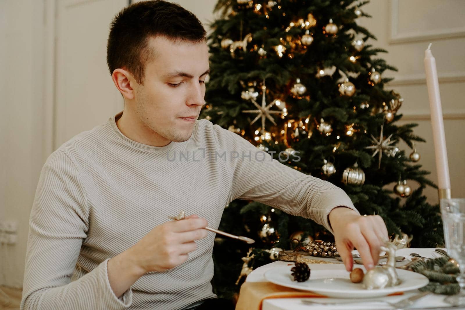 Man at the christmas table. Christmas tree on golden bright interior by natali_brill
