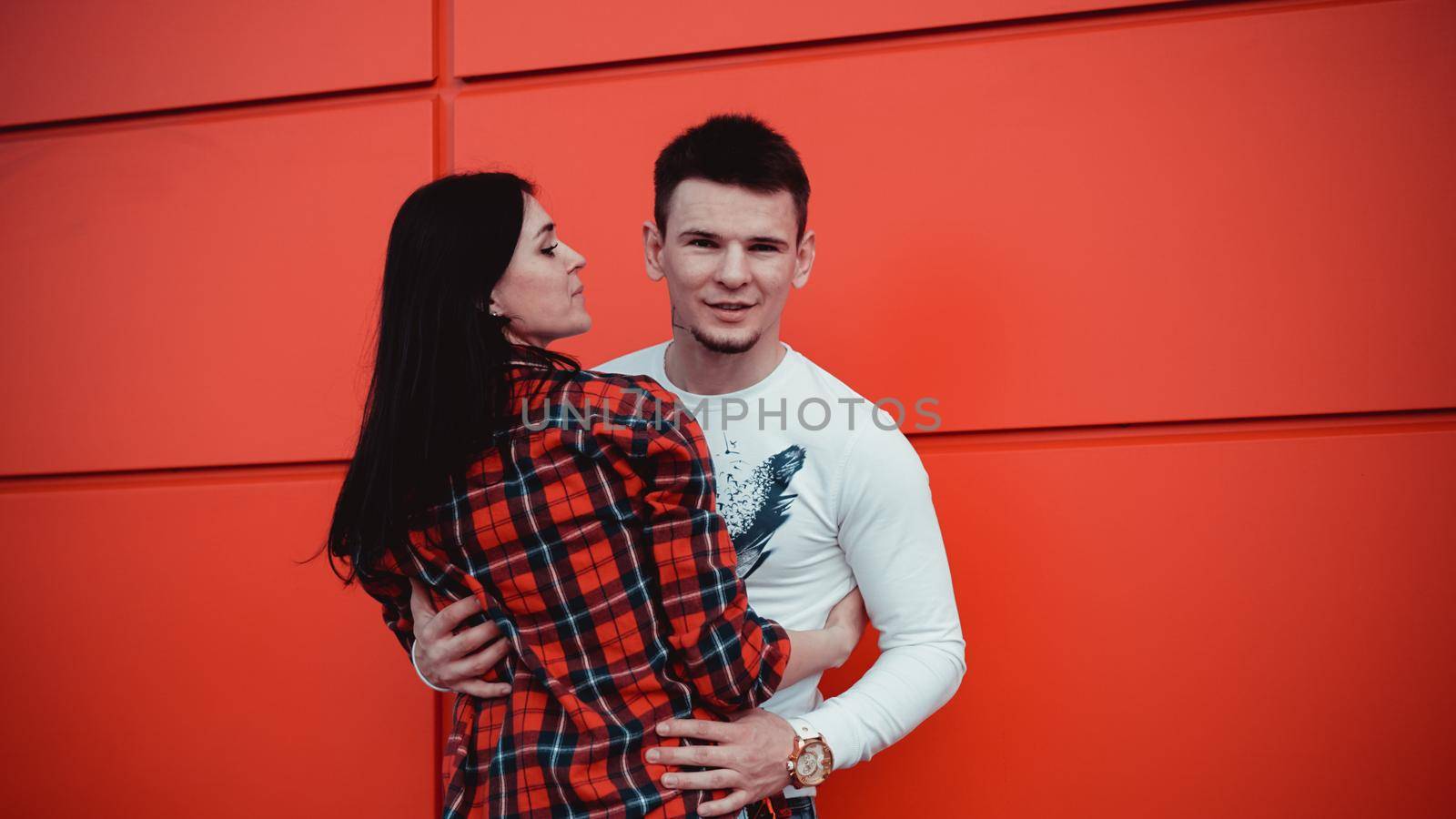 Couple dating and hugging in love in an urban in a sunny day - red background