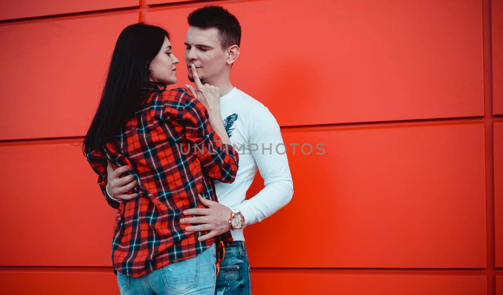Couple dating and hugging in love in an urban in a sunny day - red background