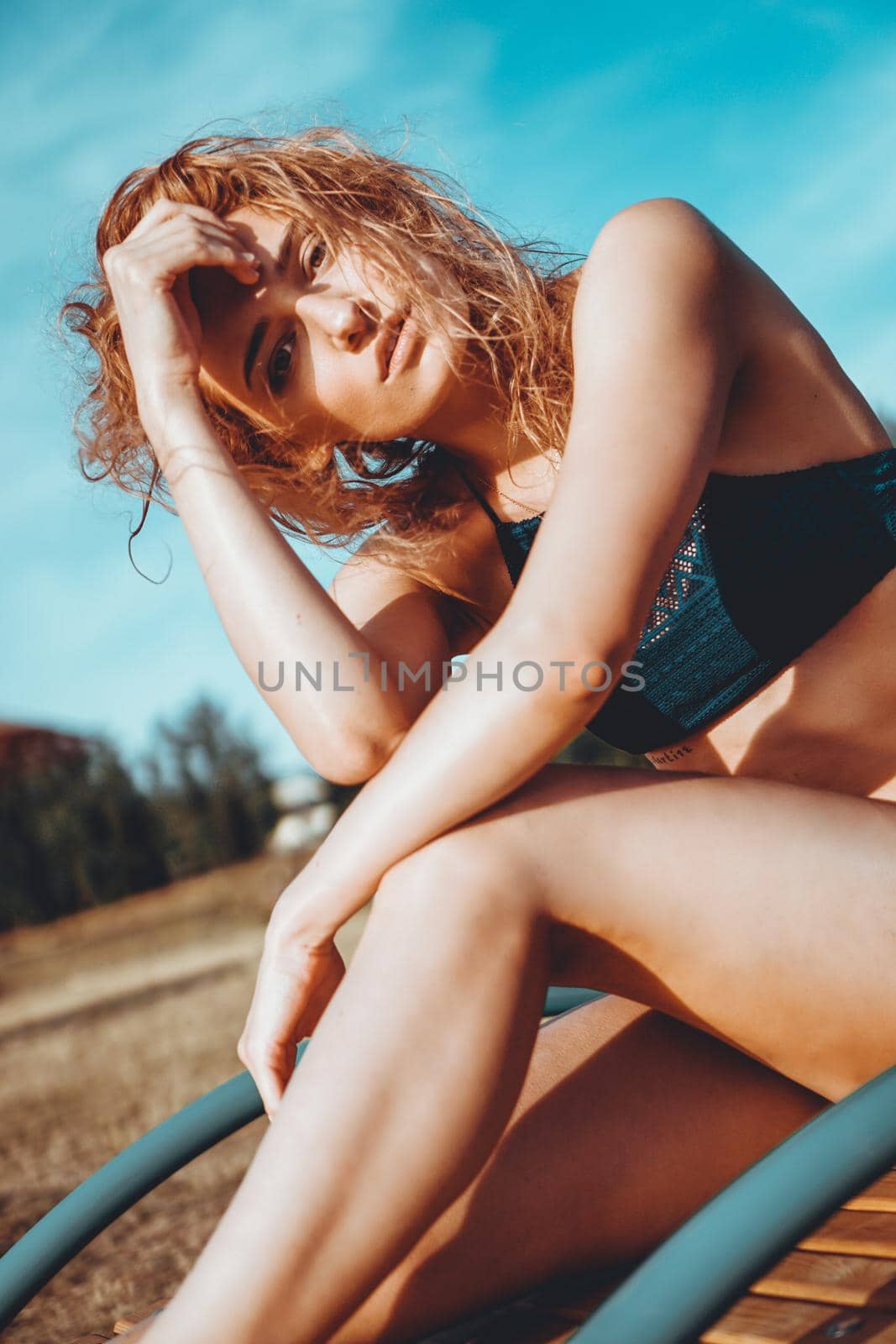 Portrait of beautiful young woman in the swimsuit relaxing on the beach - fashion portrait