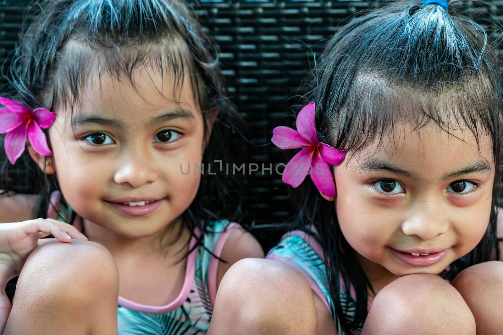 Little girl twins with large pink flower behind ear