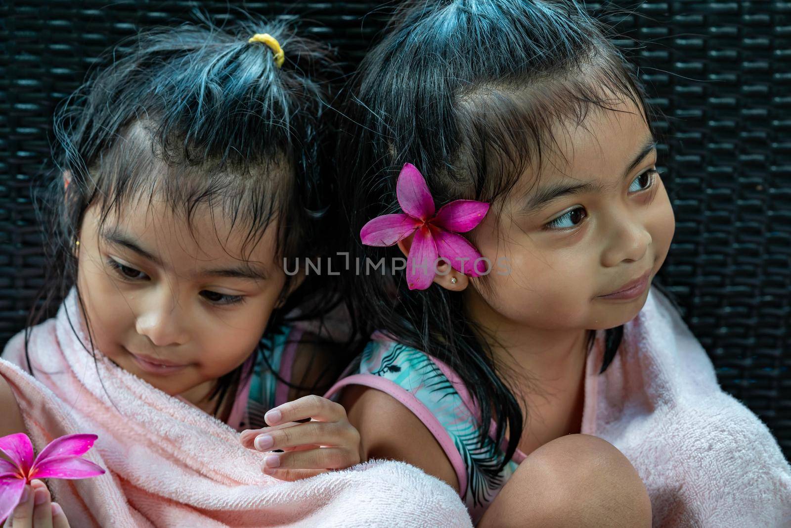 Little girl twins with large pink flower behind ear by billroque